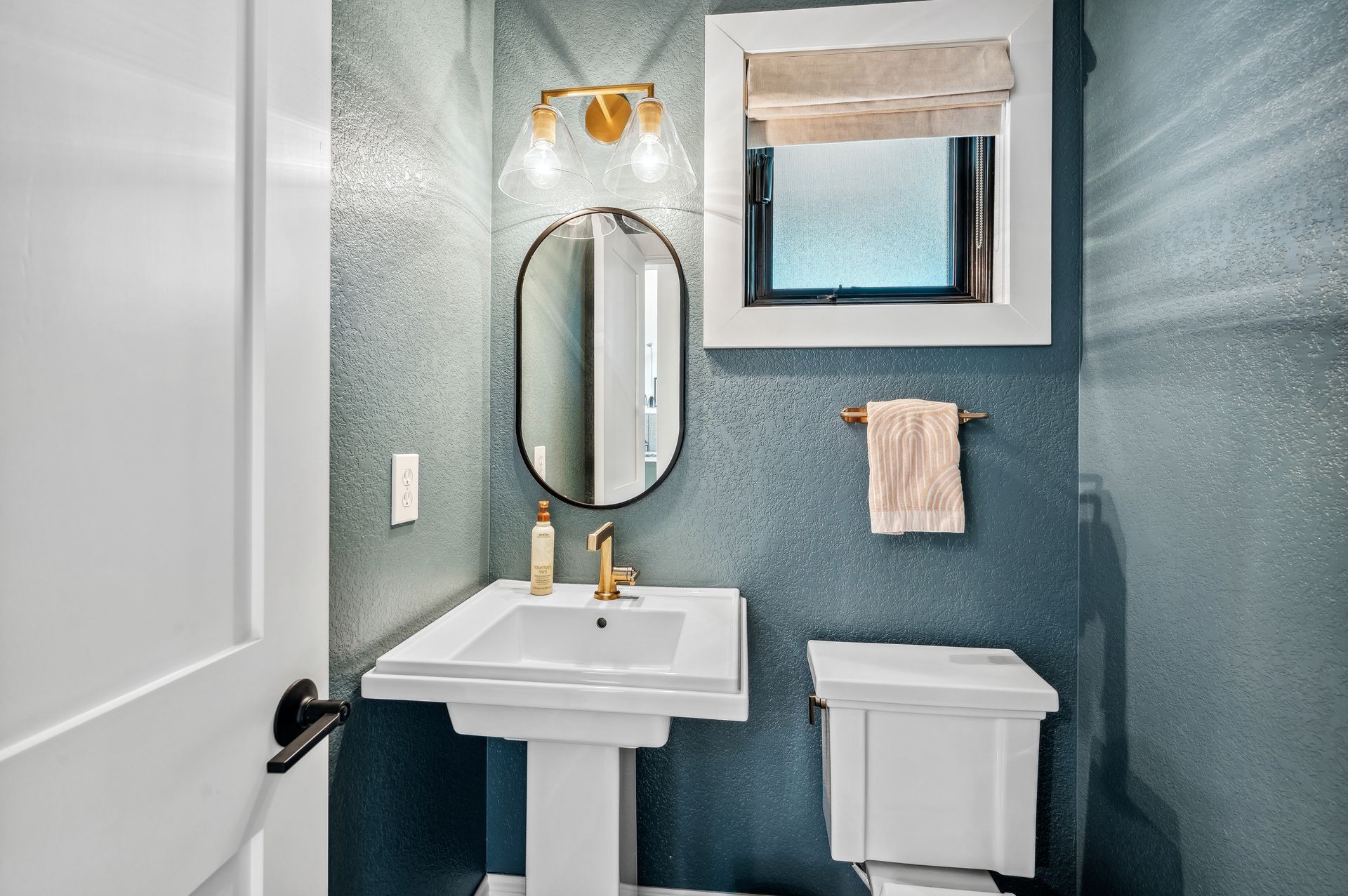 A bathroom with a sink , toilet , mirror and window.