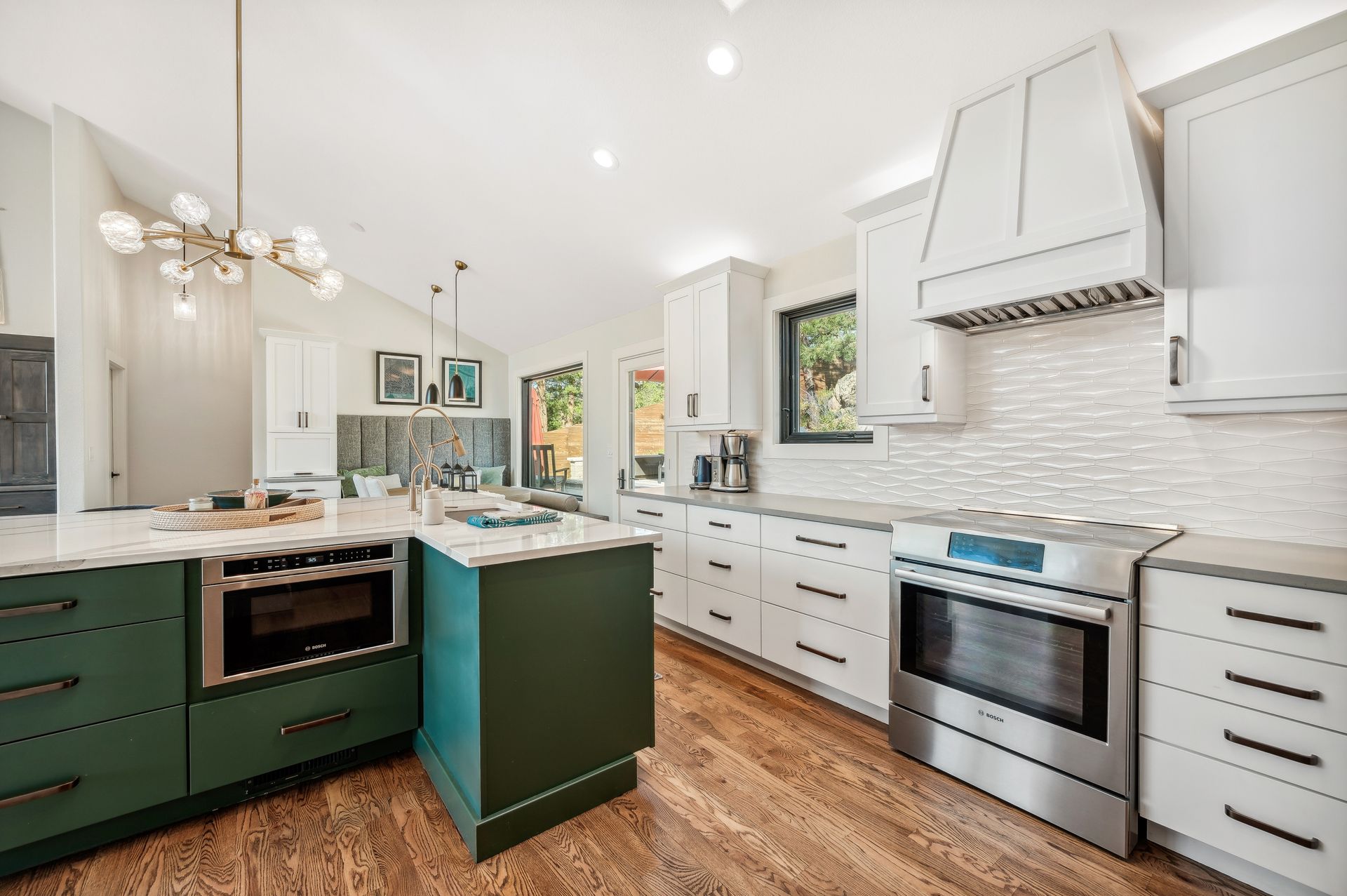 A kitchen with green cabinets , white cabinets , stainless steel appliances and a large island.