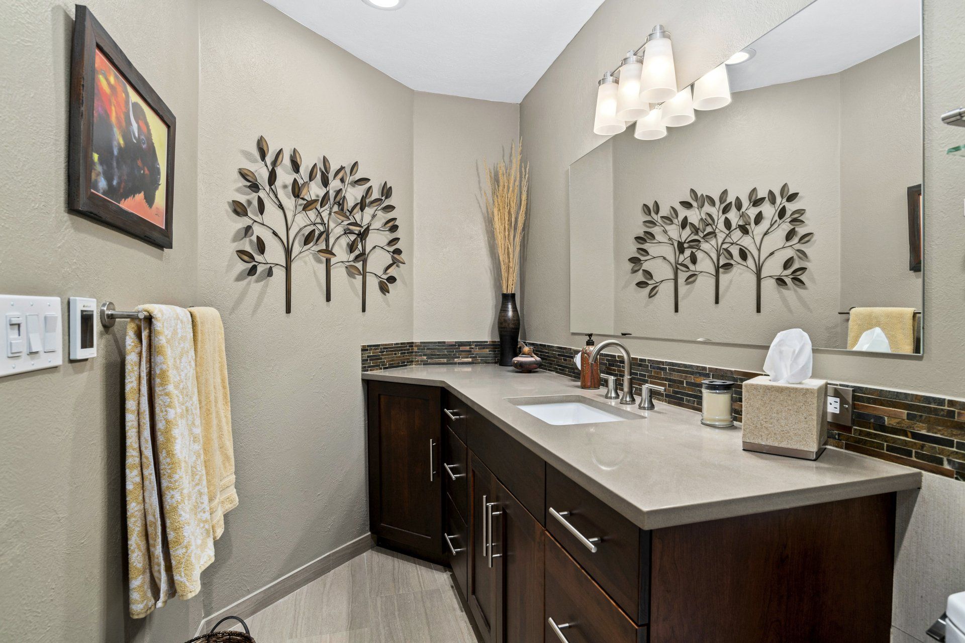 A bathroom with two sinks , a mirror , and a picture on the wall.