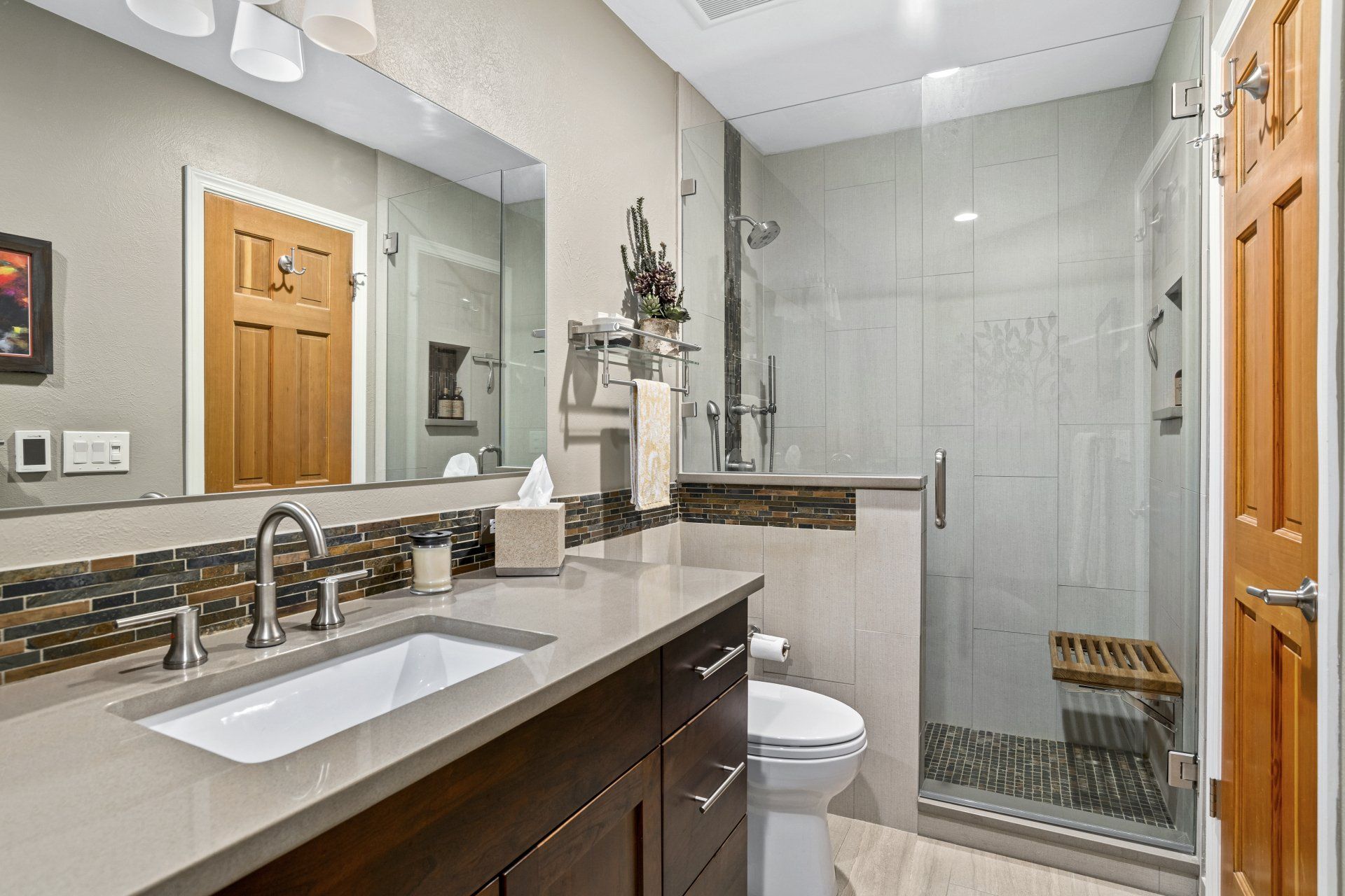 A bathroom with a sink , toilet , shower and mirror.