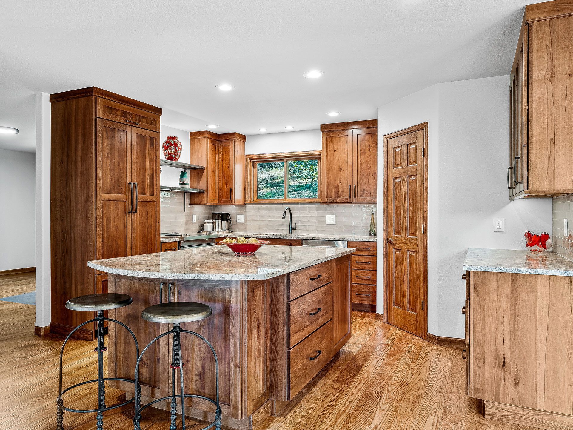A kitchen with wooden cabinets, granite counter tops, and a large island.