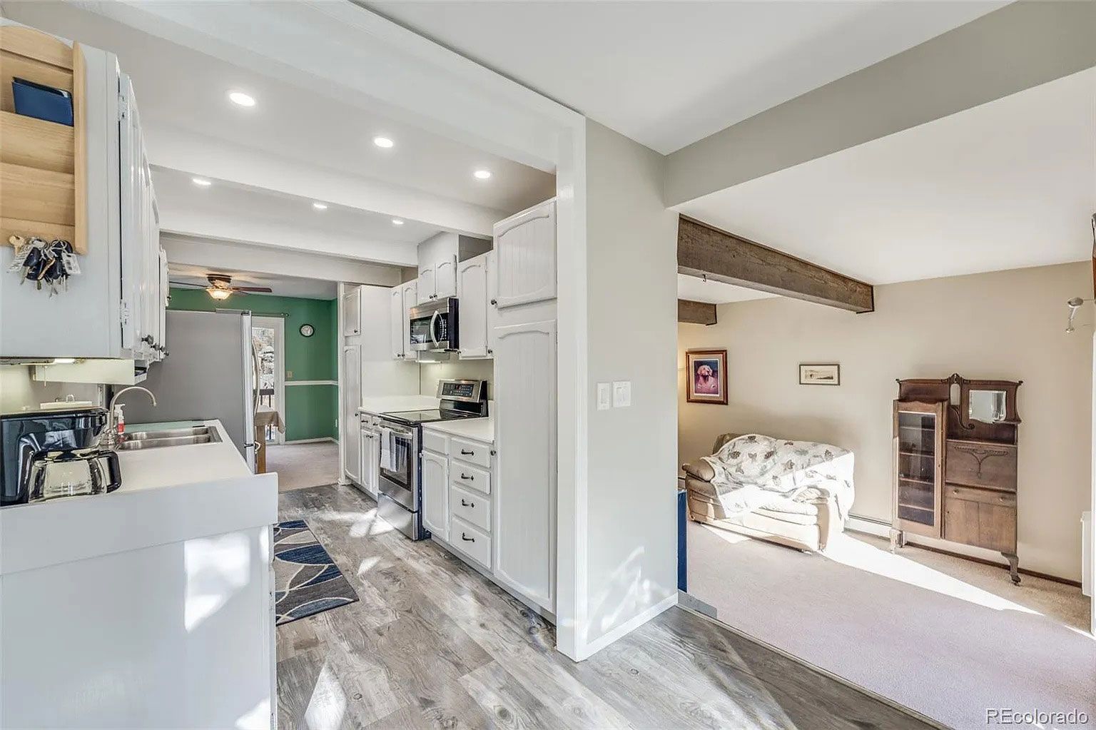 A kitchen with white cabinets and a couch in the living room.