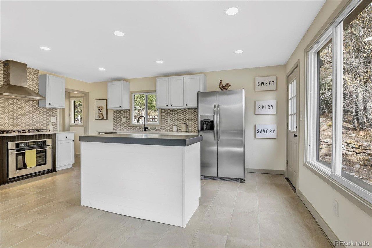 A kitchen with a large island and a stainless steel refrigerator