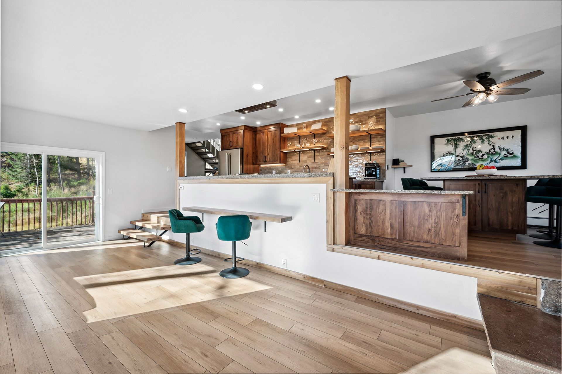 A living room with hardwood floors and a kitchen with a sliding glass door.