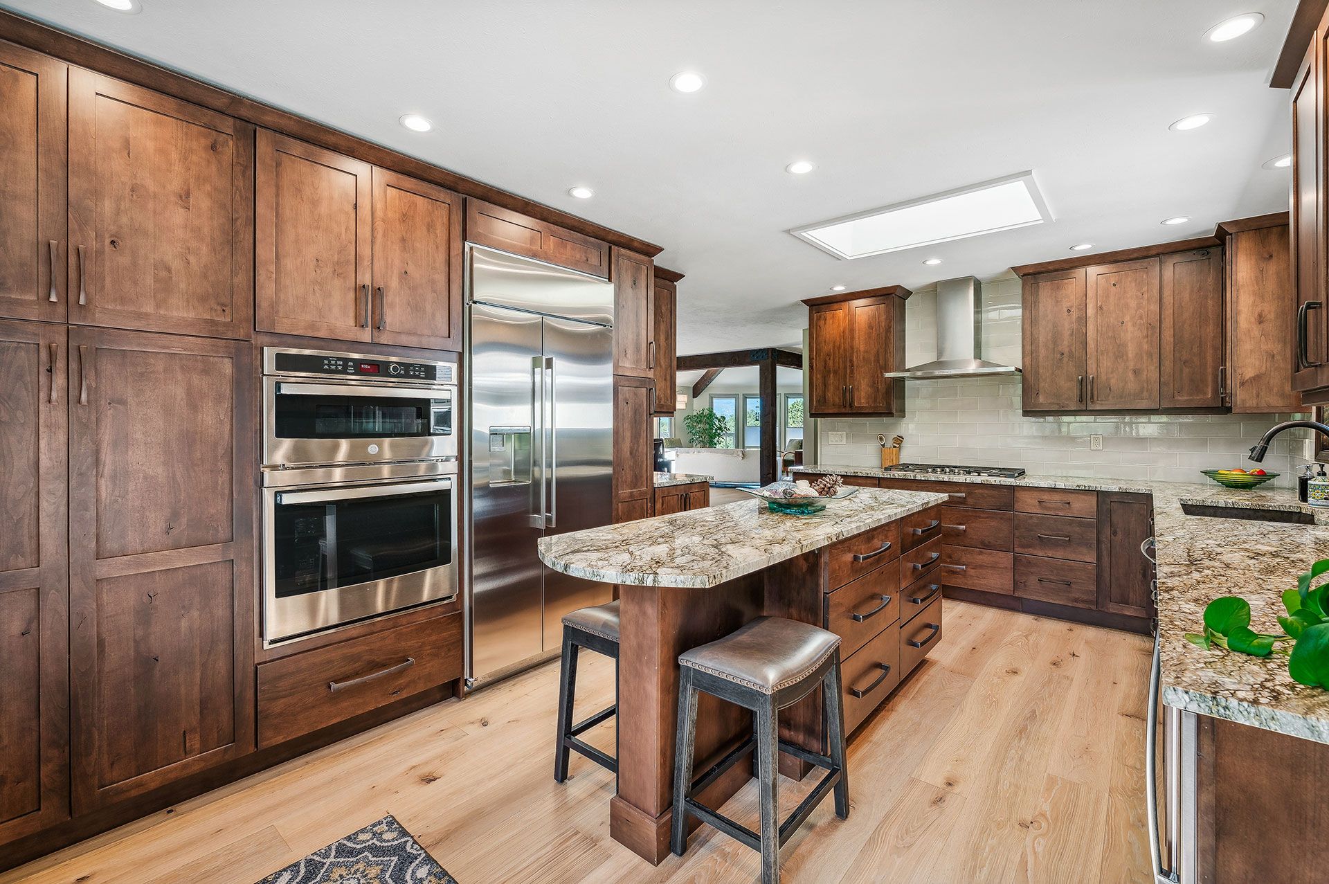 A kitchen with wooden cabinets , granite counter tops , stainless steel appliances and a large island.