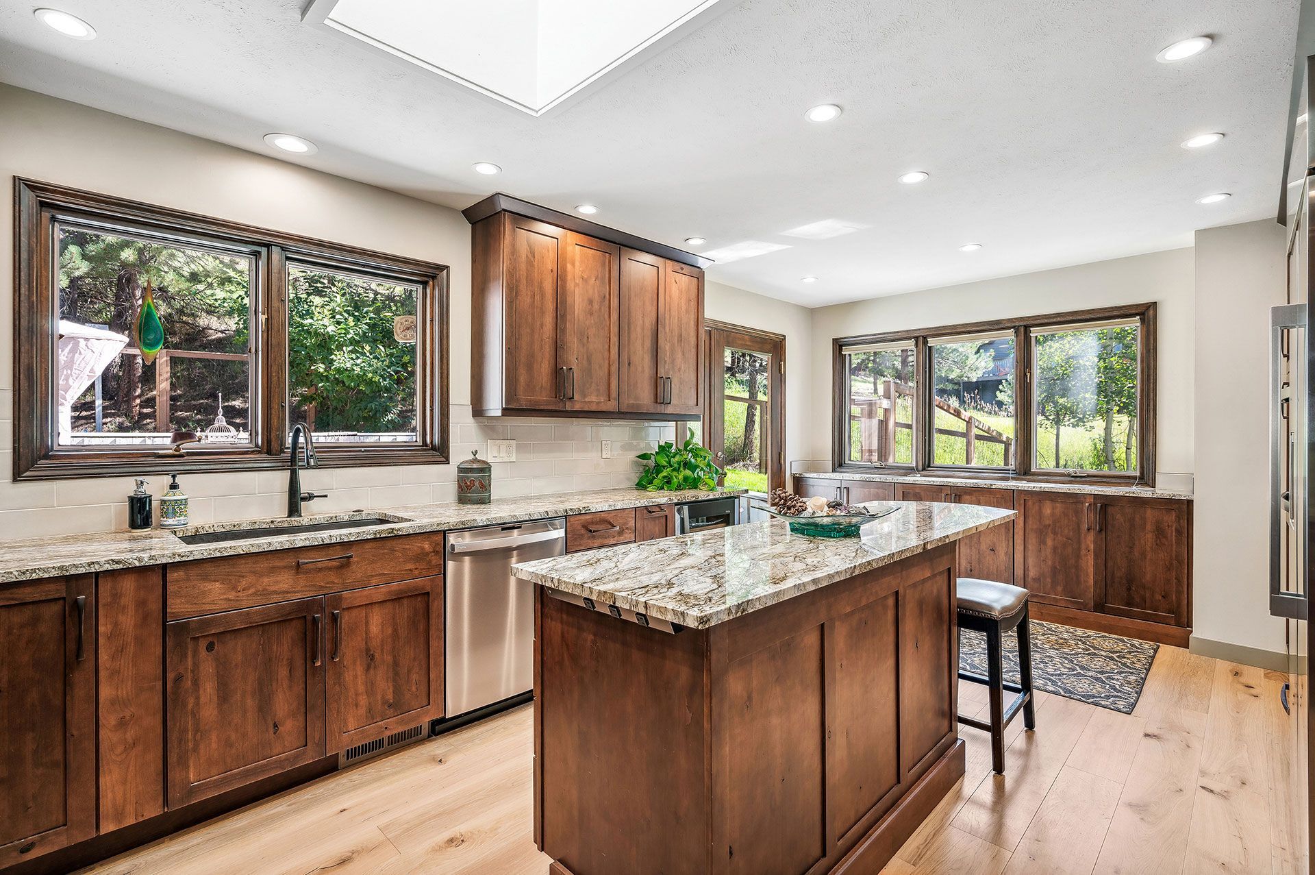 A kitchen with wooden cabinets , granite counter tops , stainless steel appliances and a large island.
