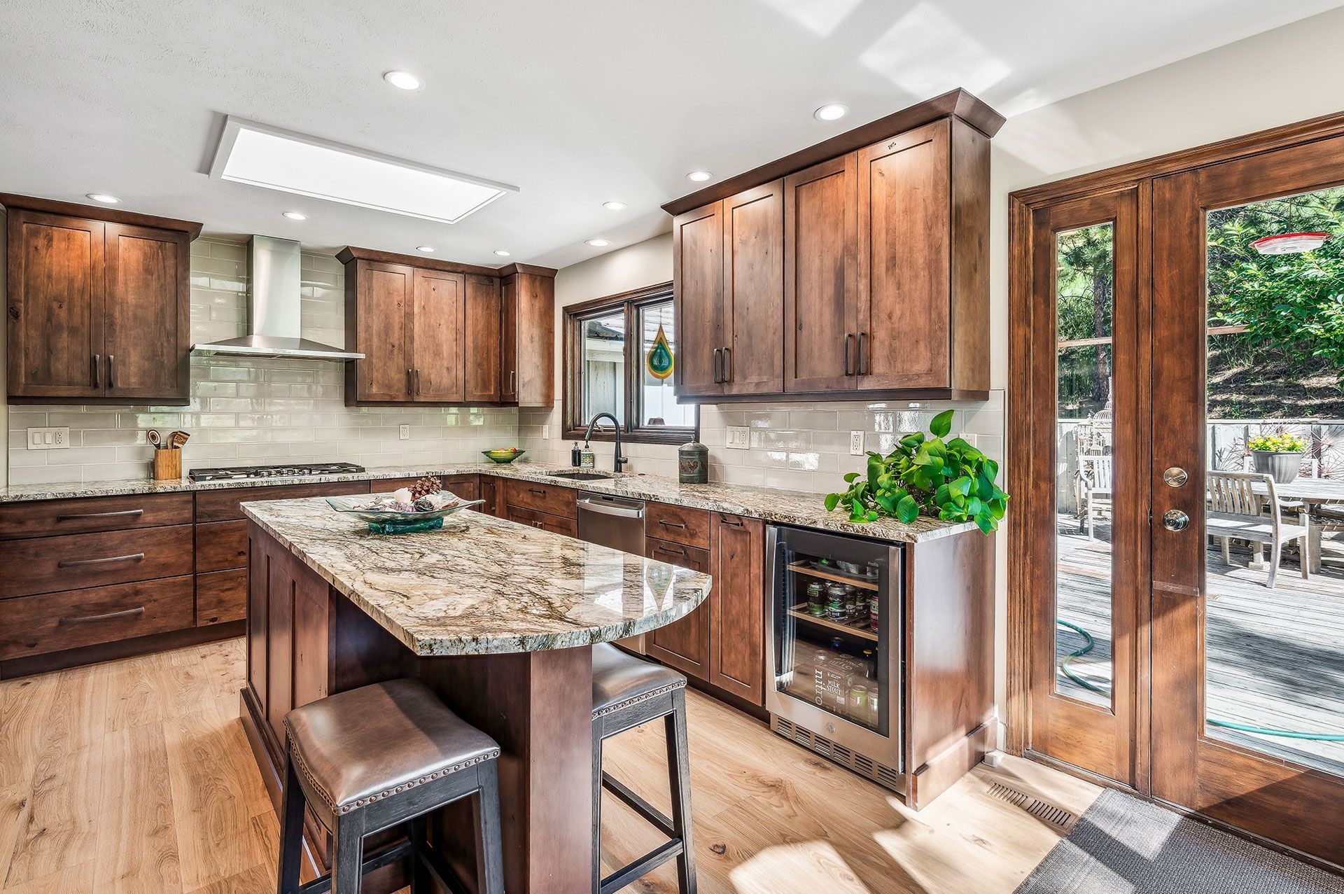 A kitchen with wooden cabinets , granite counter tops , stainless steel appliances and a large island.