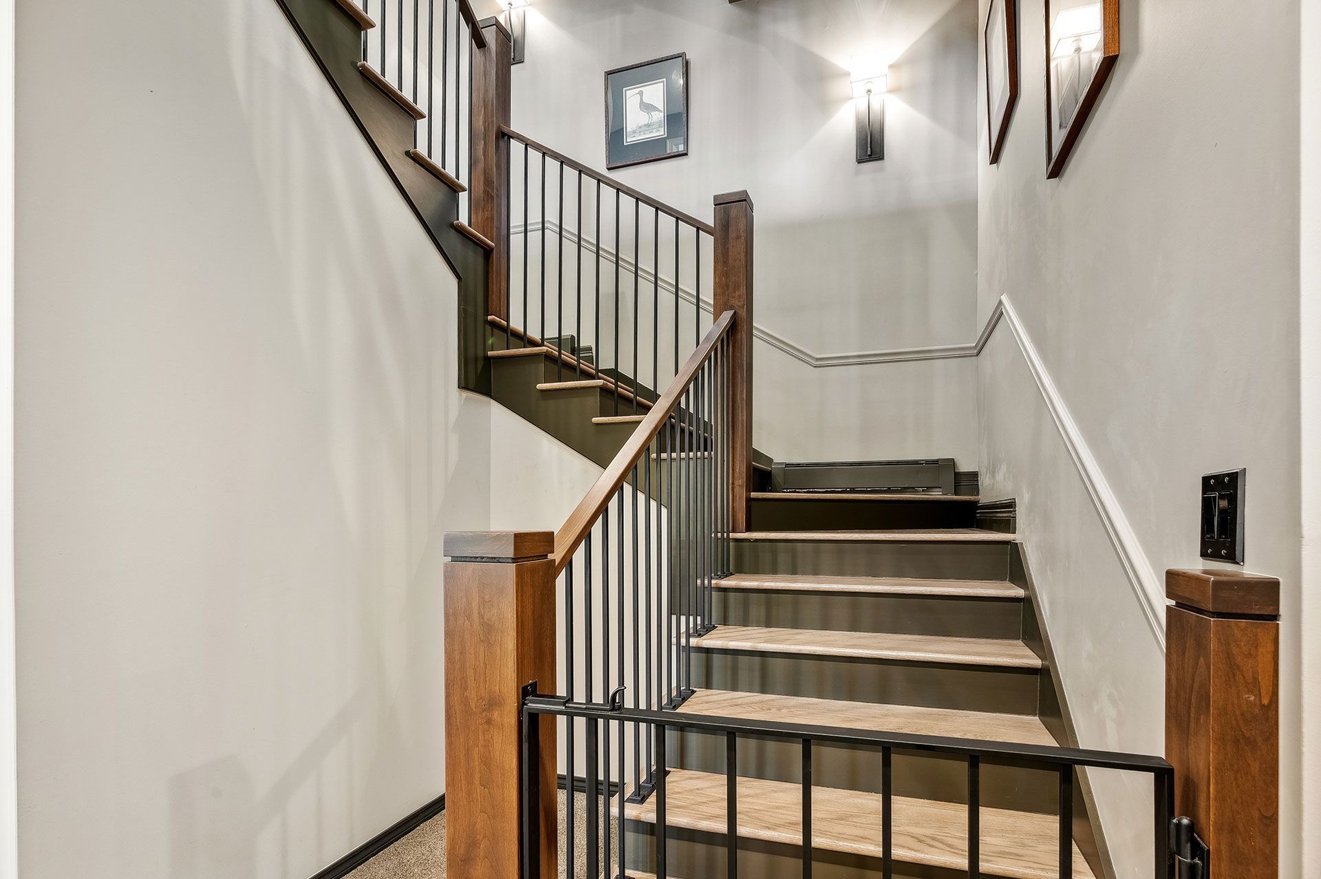 A staircase with a metal railing and a wooden handrail leading up to the second floor of a house.