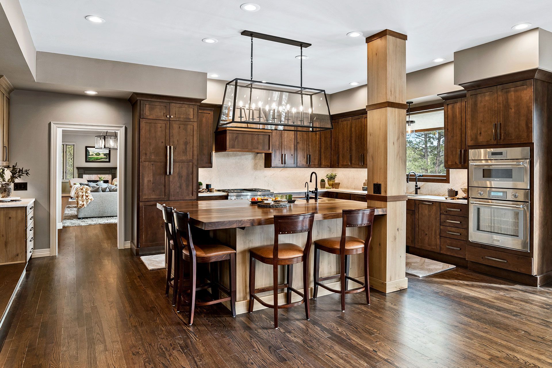 A kitchen with wooden cabinets , hardwood floors , stainless steel appliances and a large island.