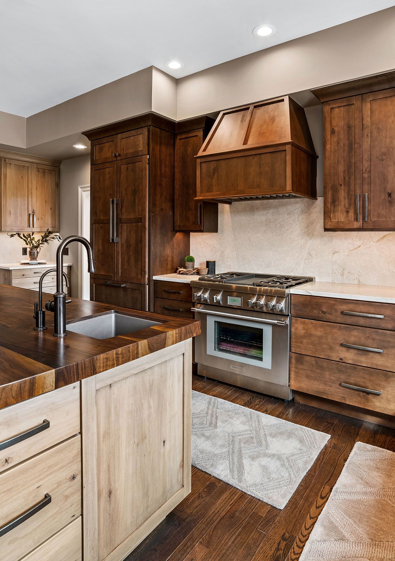 A kitchen with wooden cabinets , stainless steel appliances , a sink , and a stove.