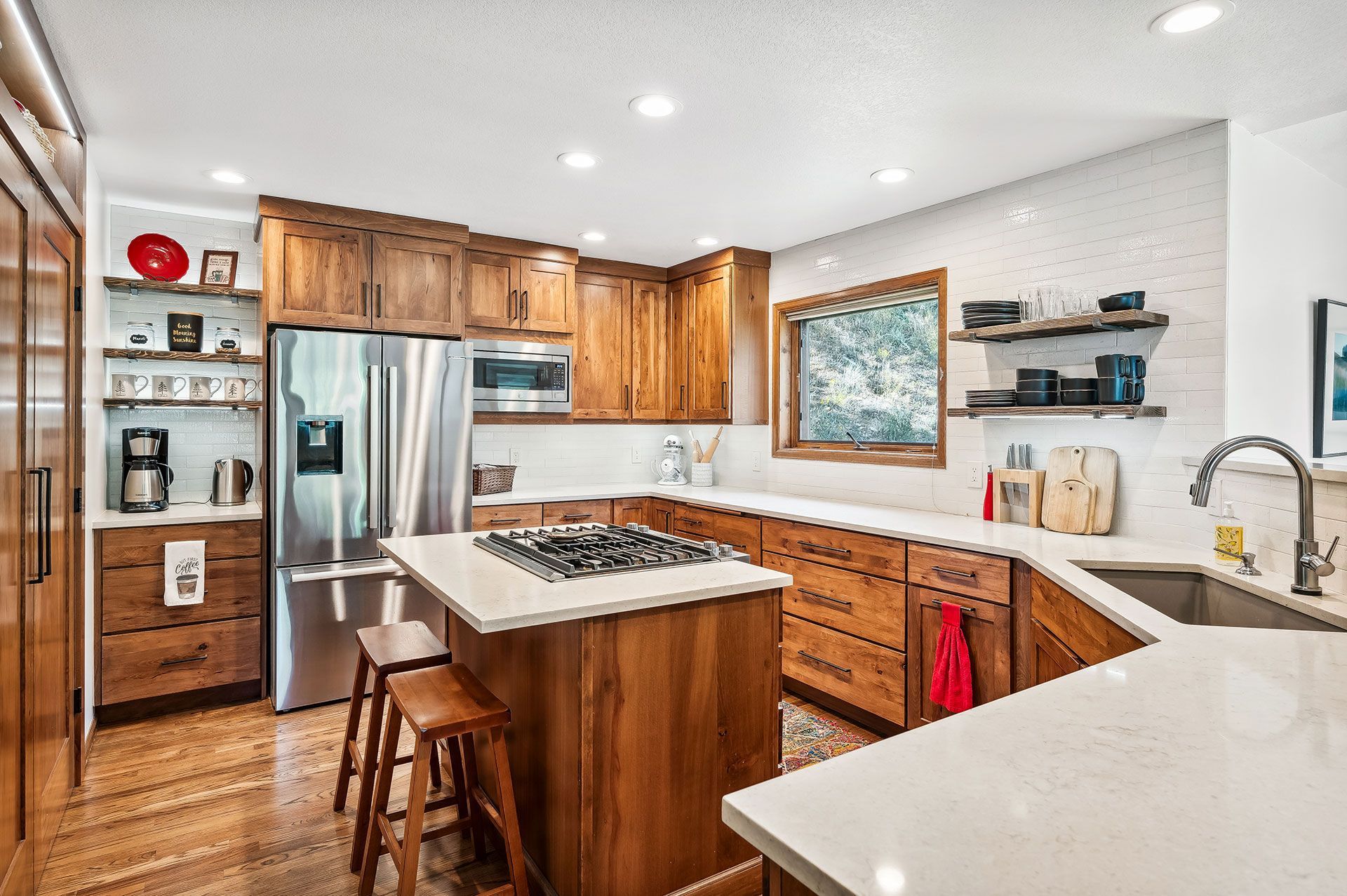 A kitchen with wooden cabinets , stainless steel appliances , a large island , and a sink.