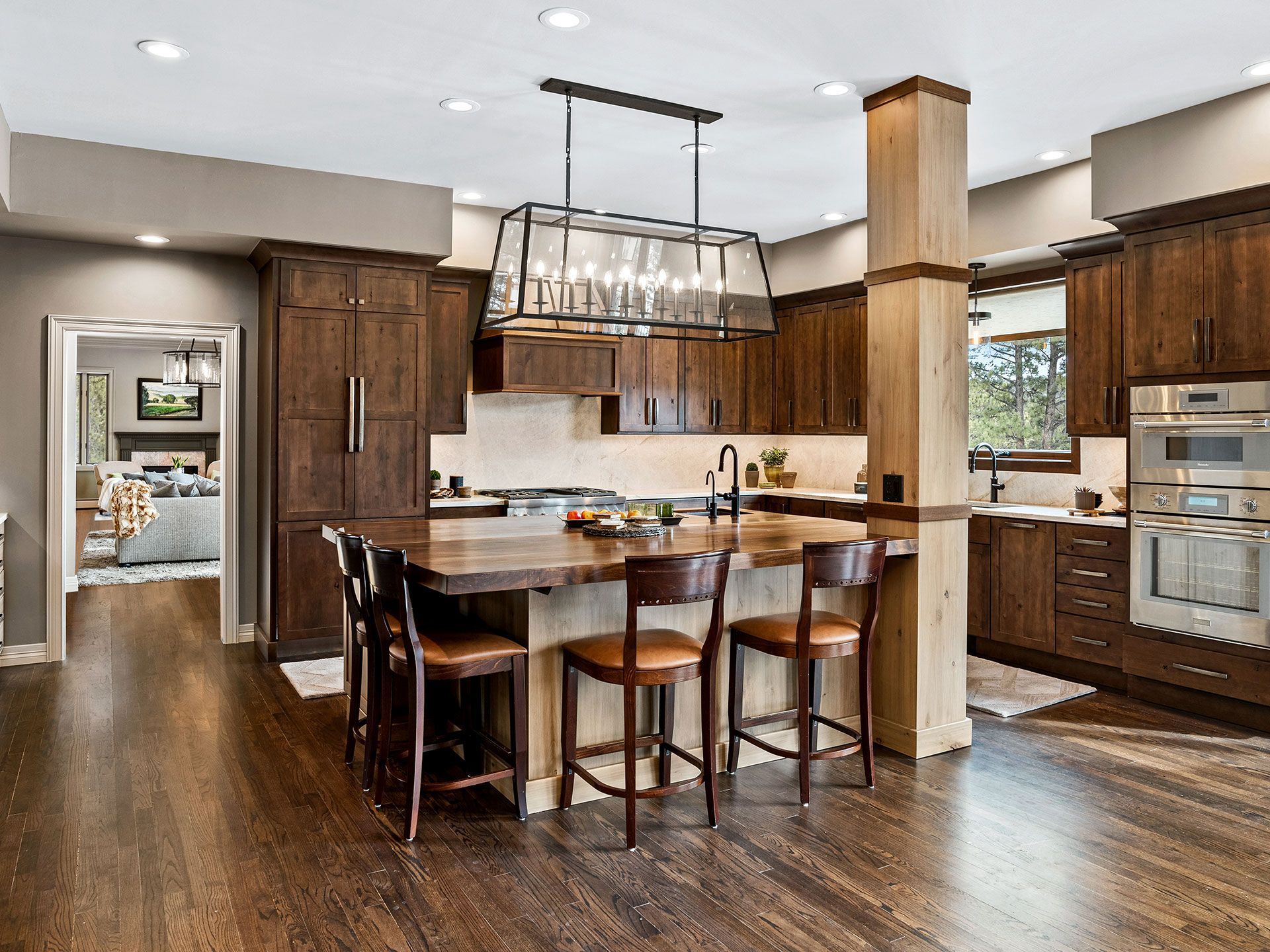 A kitchen with a large island, stools, and a chandelier.