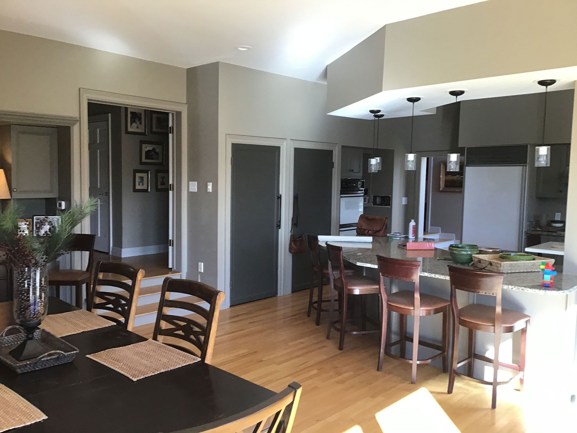 A dining room with a table and chairs and a kitchen in the background.