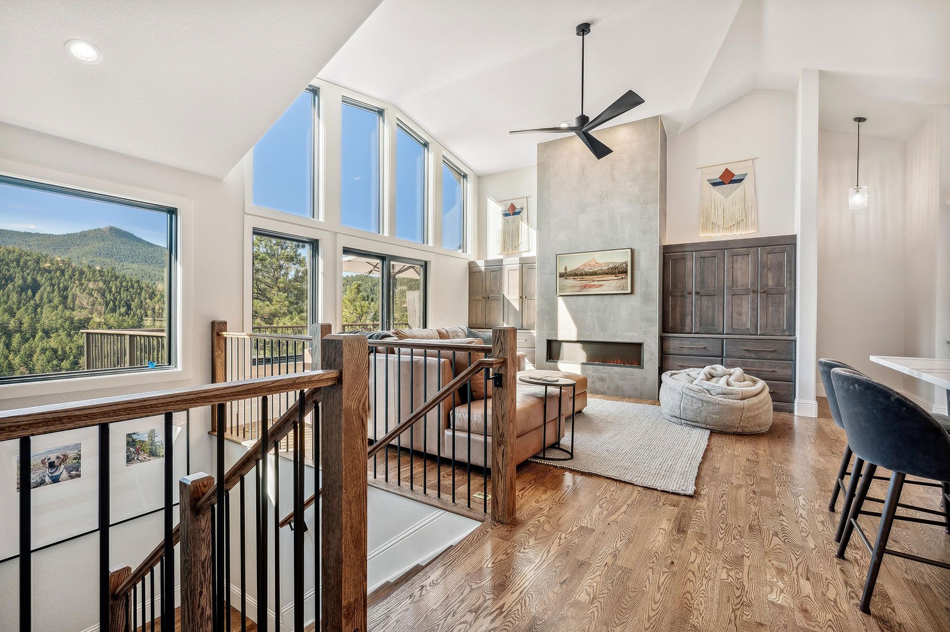 A living room with hardwood floors , a fireplace , stairs and a ceiling fan.