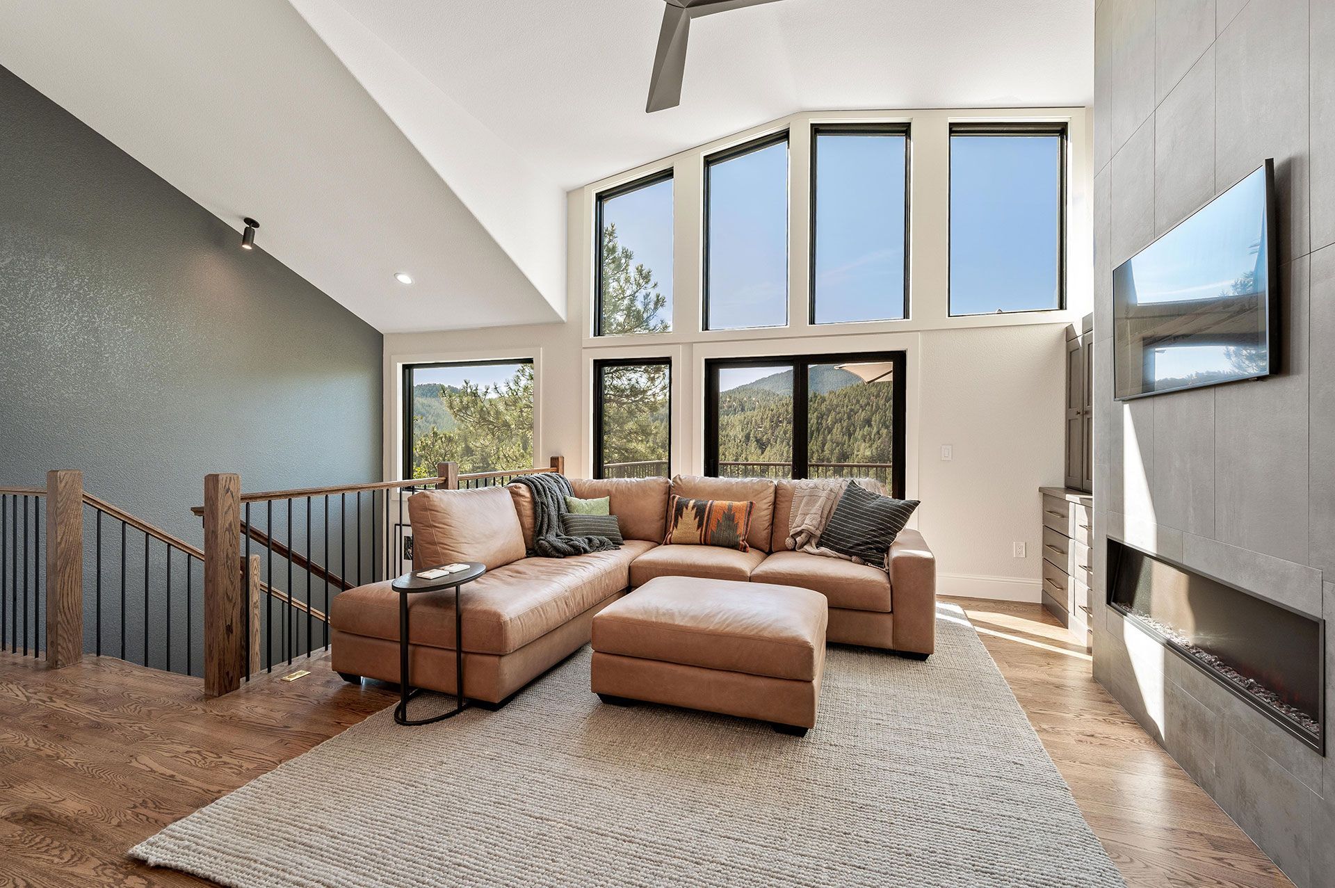 A living room with a couch , ottoman , television and stairs.