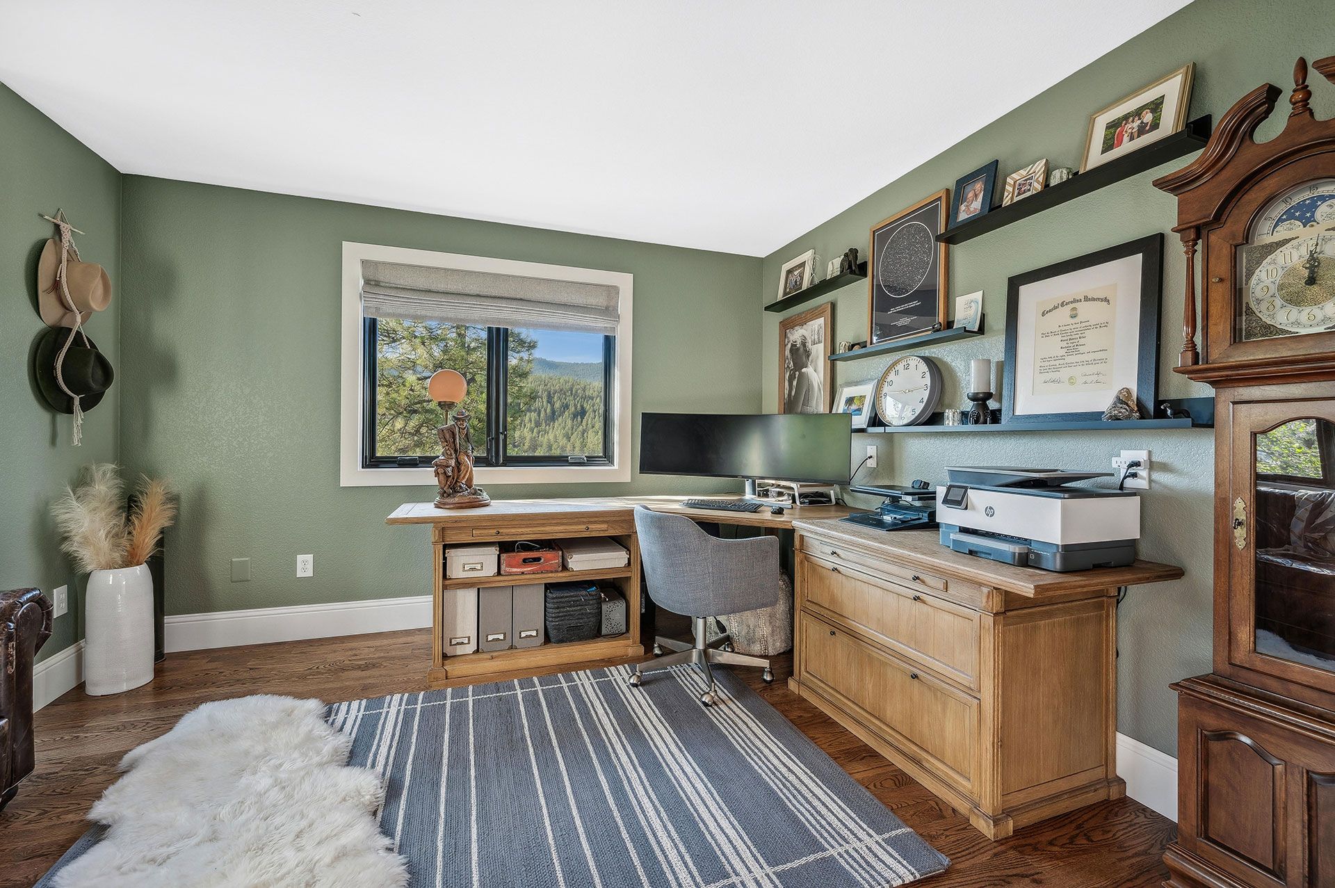 A home office with a desk , chair , printer and clock.