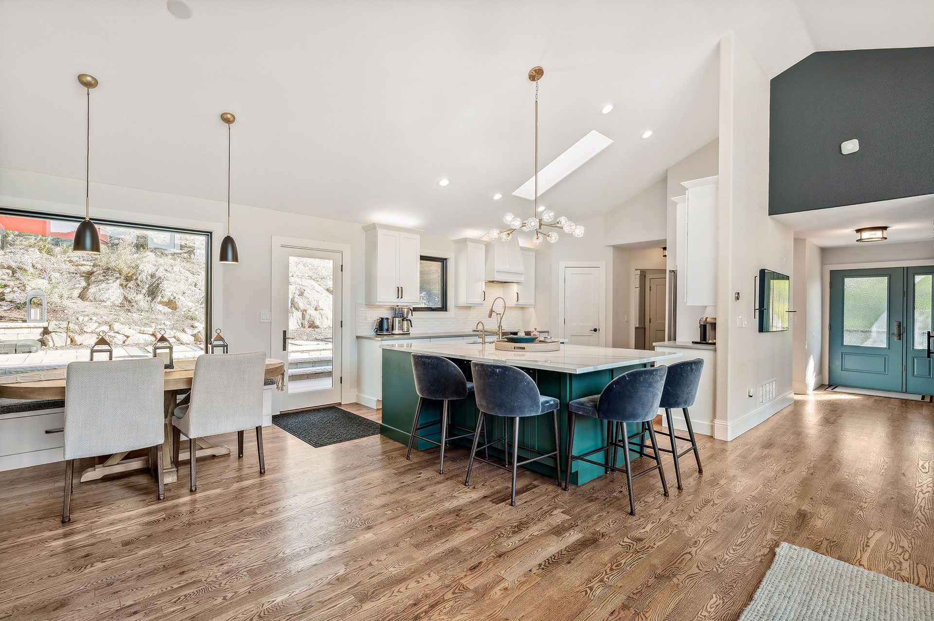 A kitchen and dining room in a house with hardwood floors and a large island.