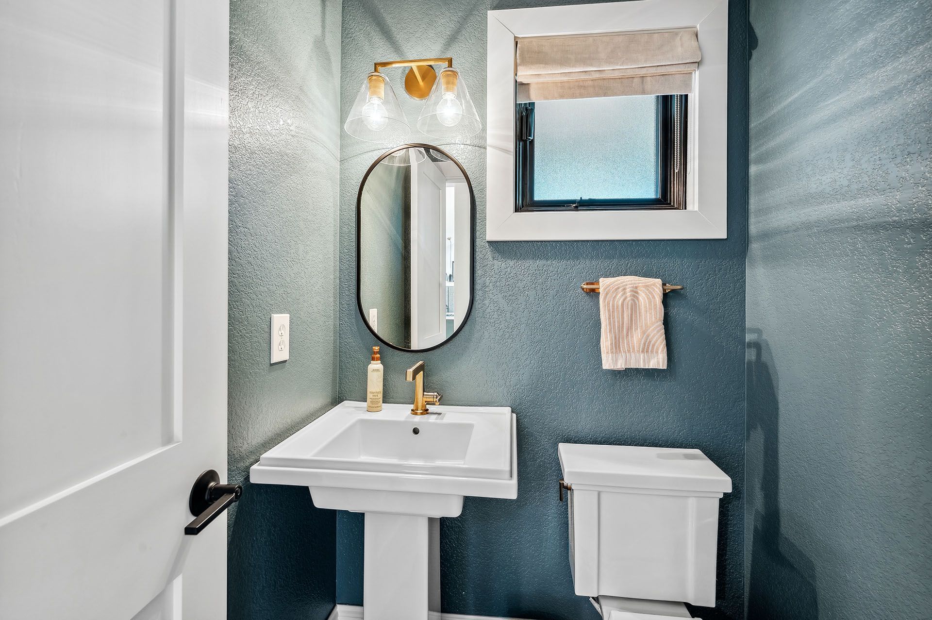 A bathroom with a sink, toilet, mirror and window