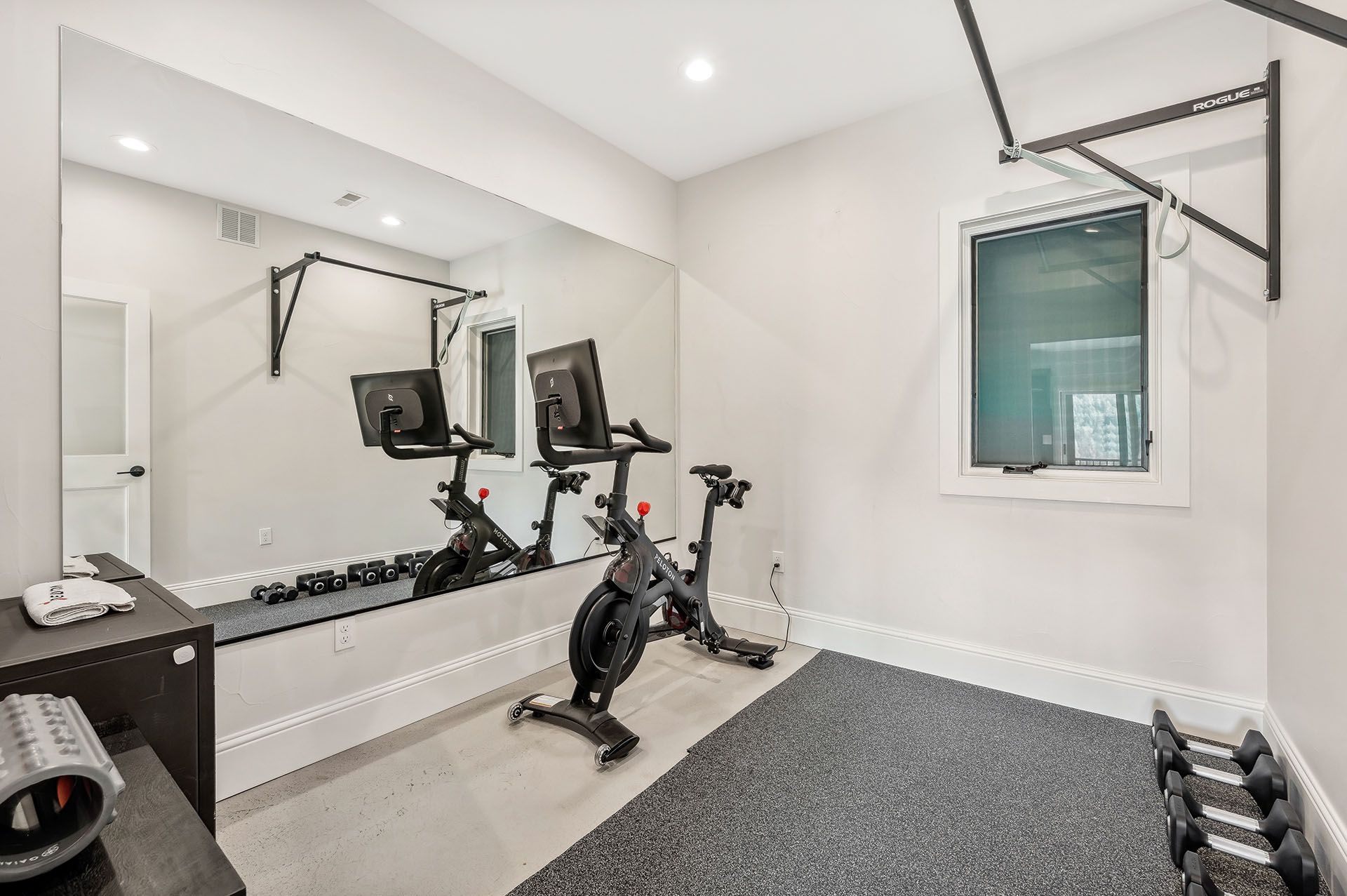 A home gym with a bicycle, dumbbells, and a large mirror