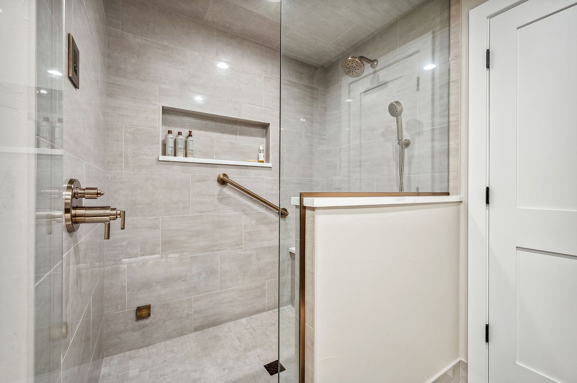 A bathroom with a walk in shower with a glass door
