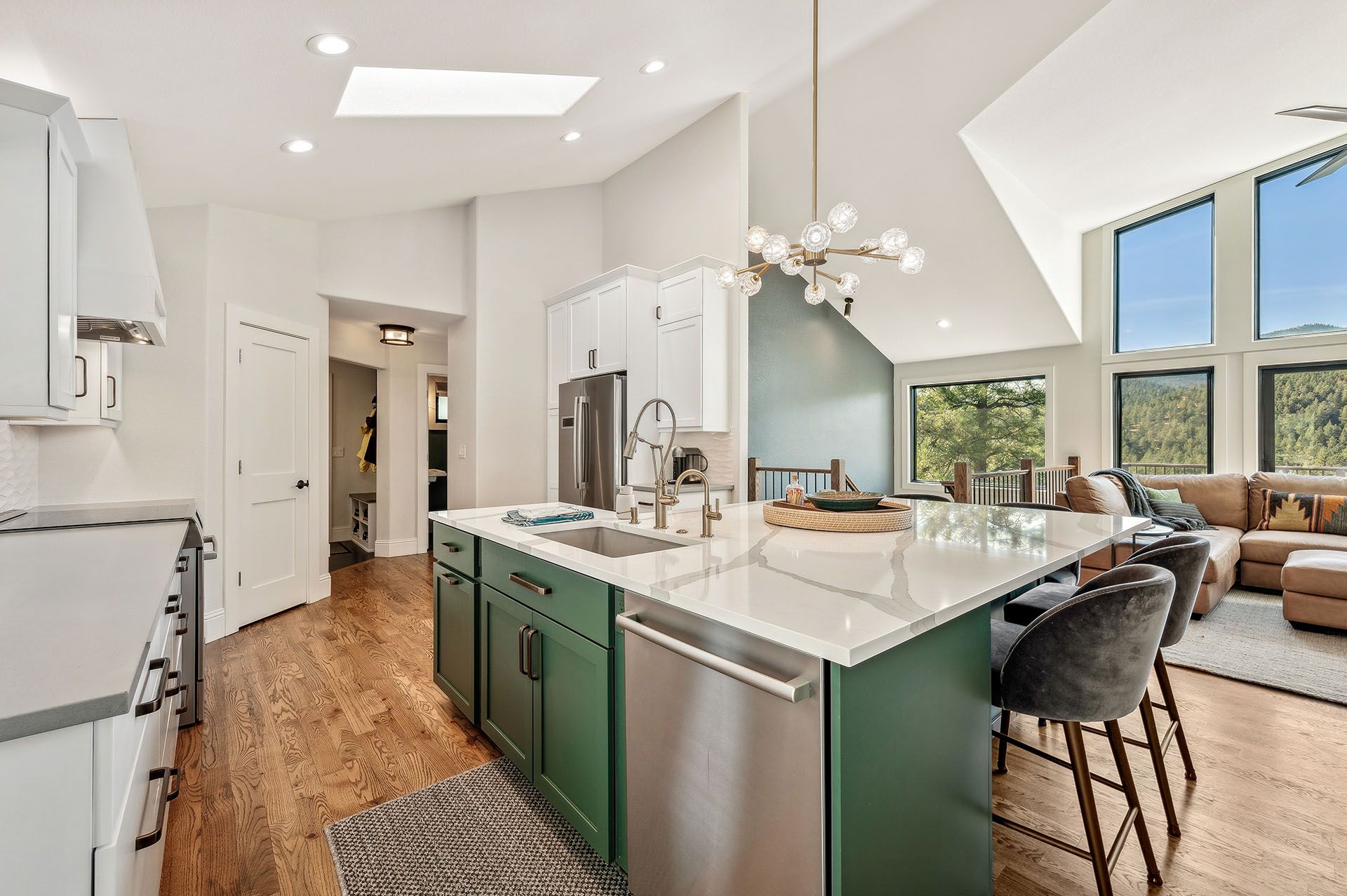 A kitchen with green cabinets, stainless steel appliances, and a large island