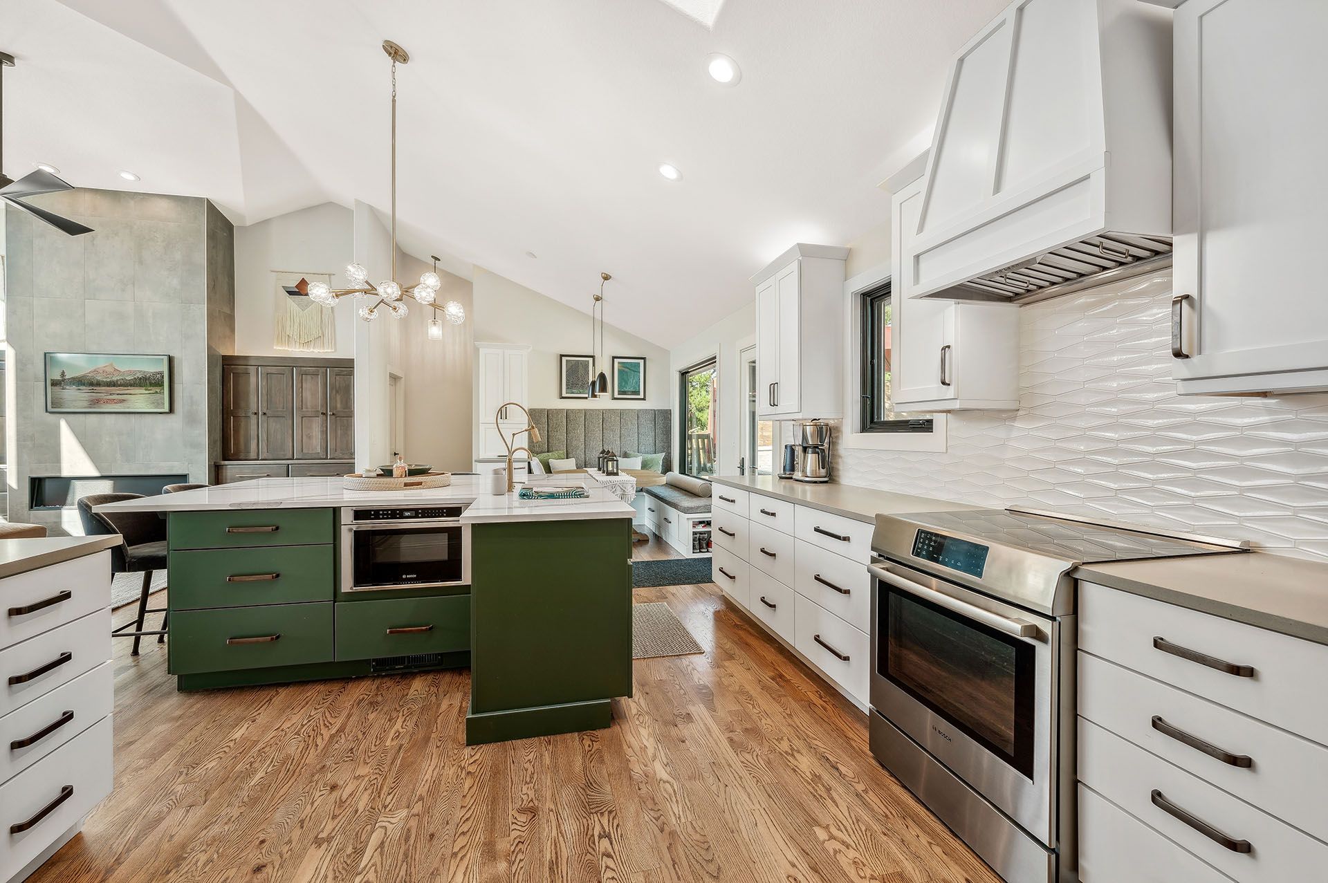 A kitchen with green cabinets, white cabinets, stainless steel appliances, and hardwood floors