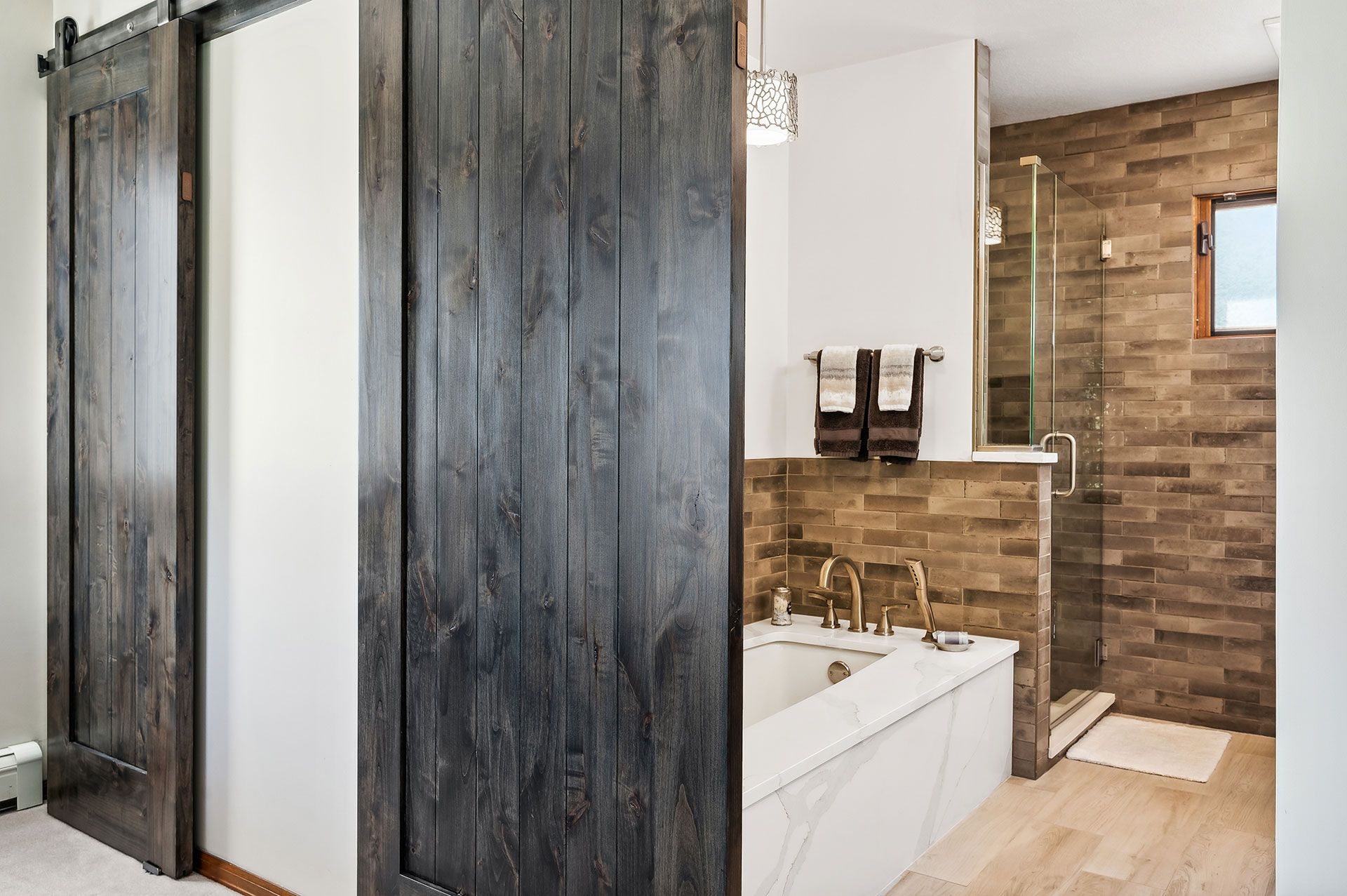 A bathroom with a sliding barn door and a bathtub.