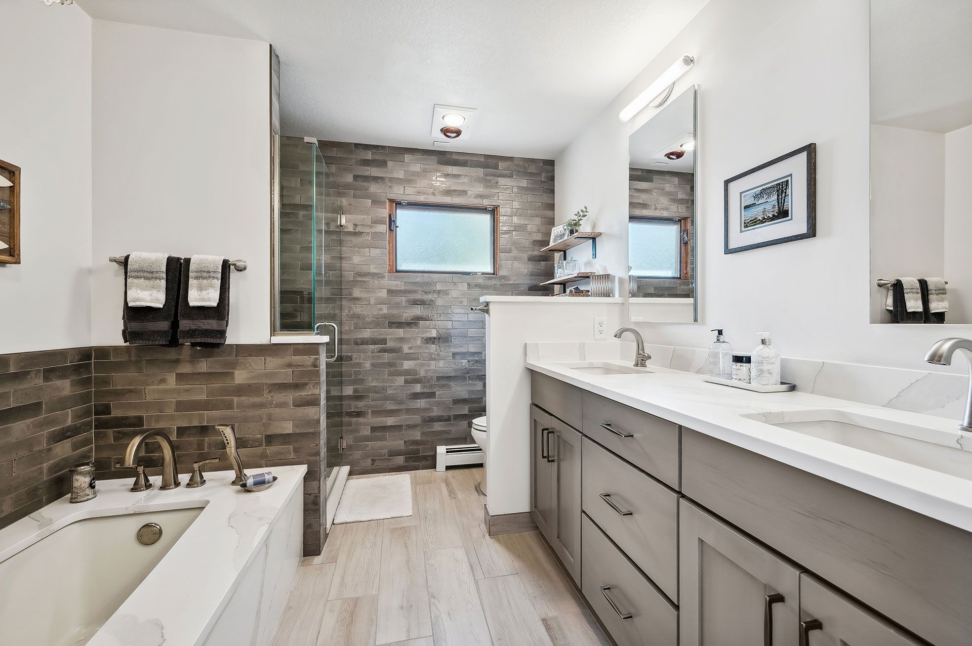 A bathroom with two sinks , a tub , and a walk in shower.