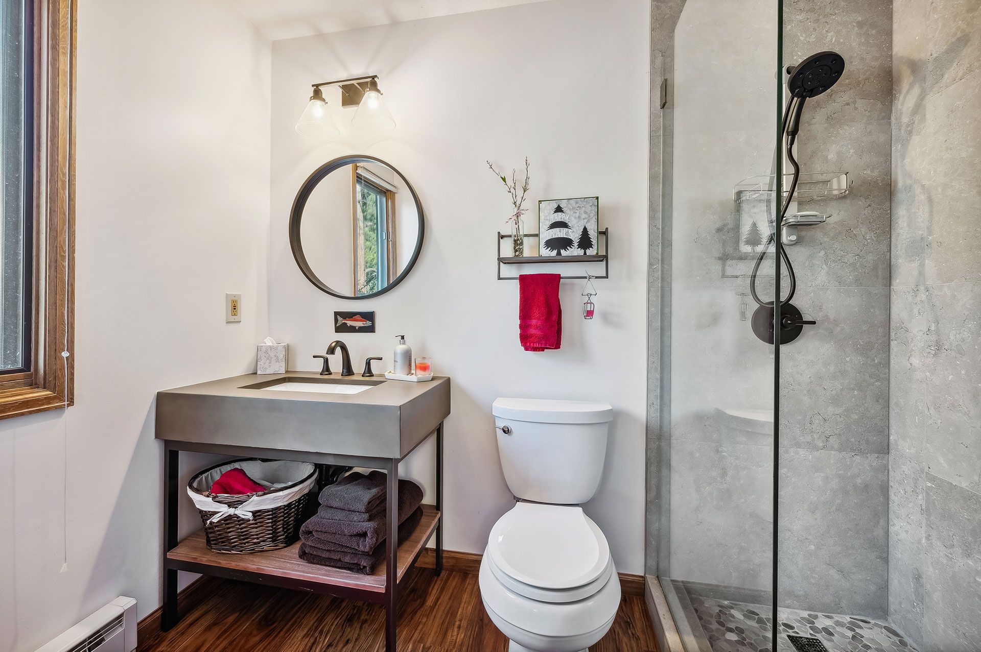 A bathroom with a toilet , sink , mirror and walk in shower.