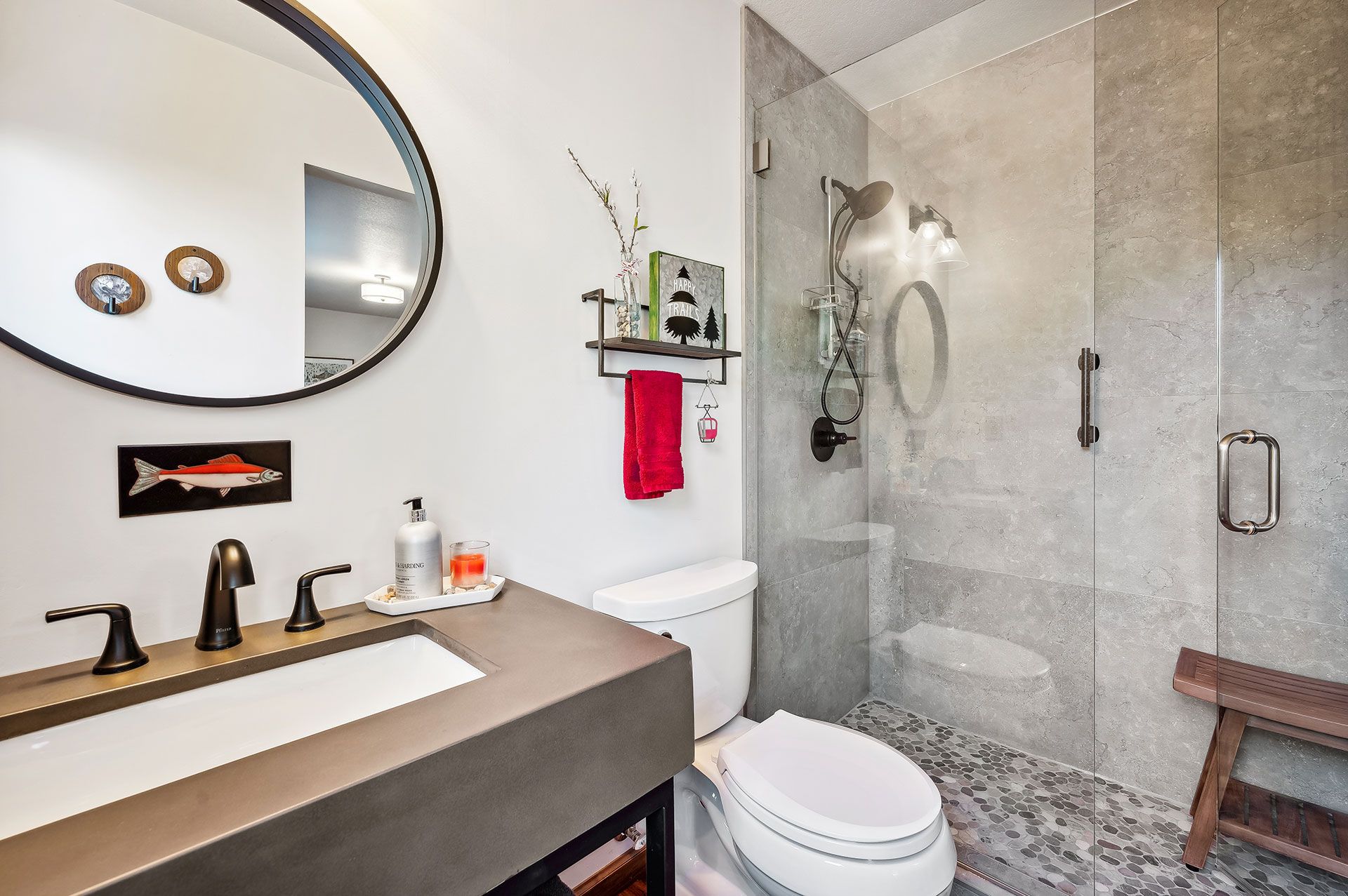 A bathroom with a toilet , sink , mirror and walk in shower.