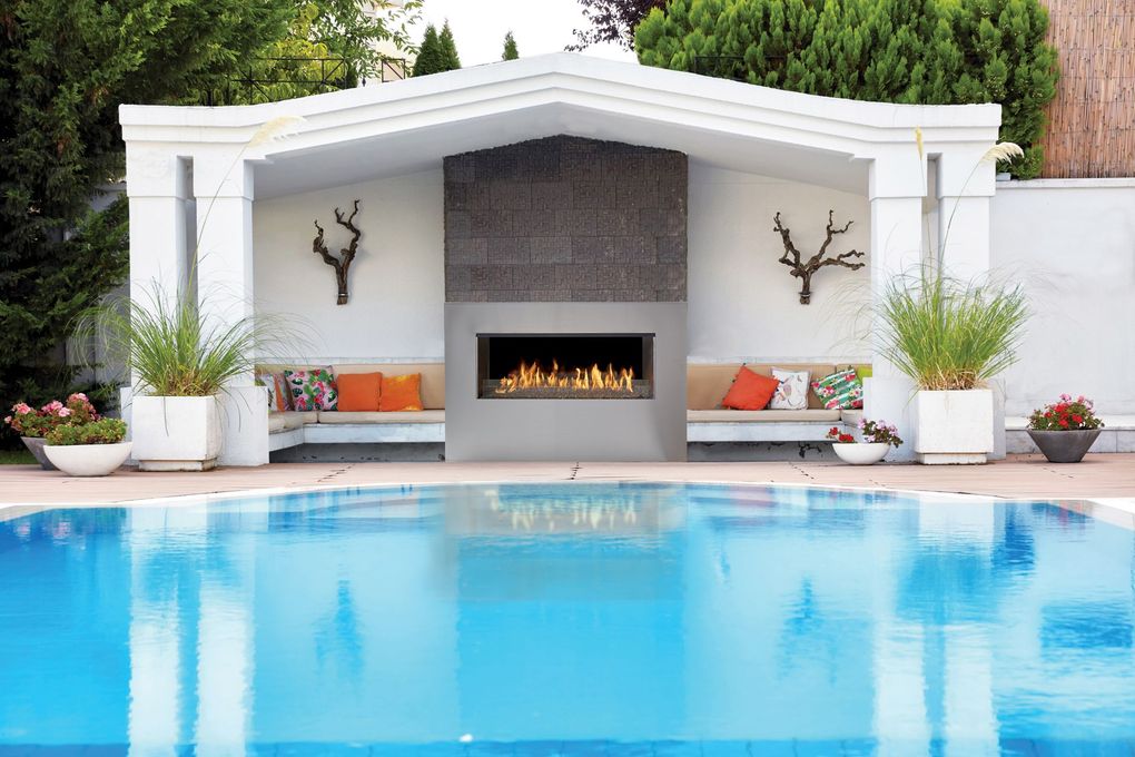 Covered patio with wood ceiling, stone fireplace, and gray seating around a central table.
