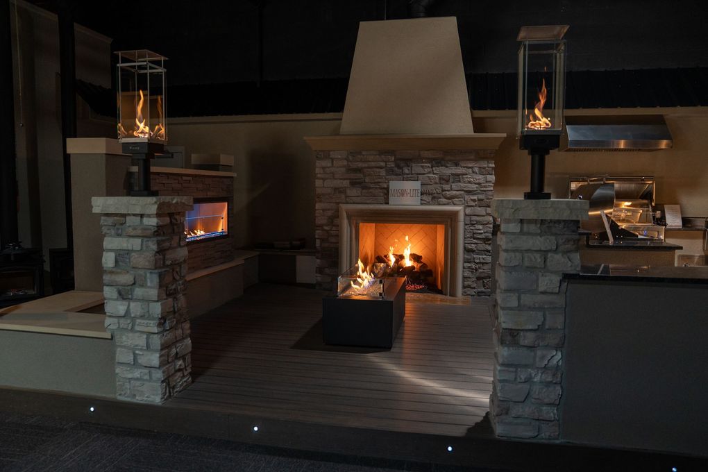 Covered patio with wood ceiling, stone fireplace, and gray seating around a central table.
