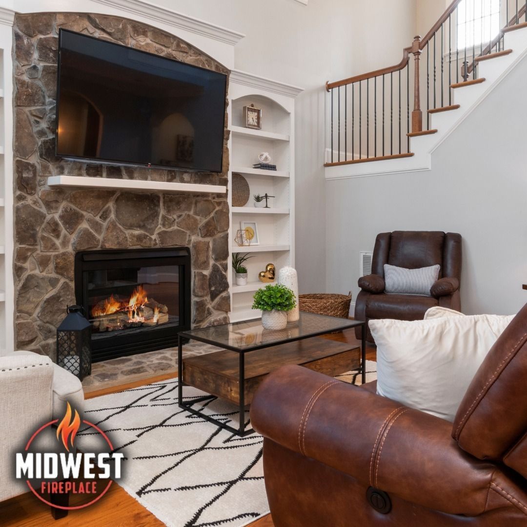 Living room with fireplace, TV, built-in shelves, staircase, and leather furniture.