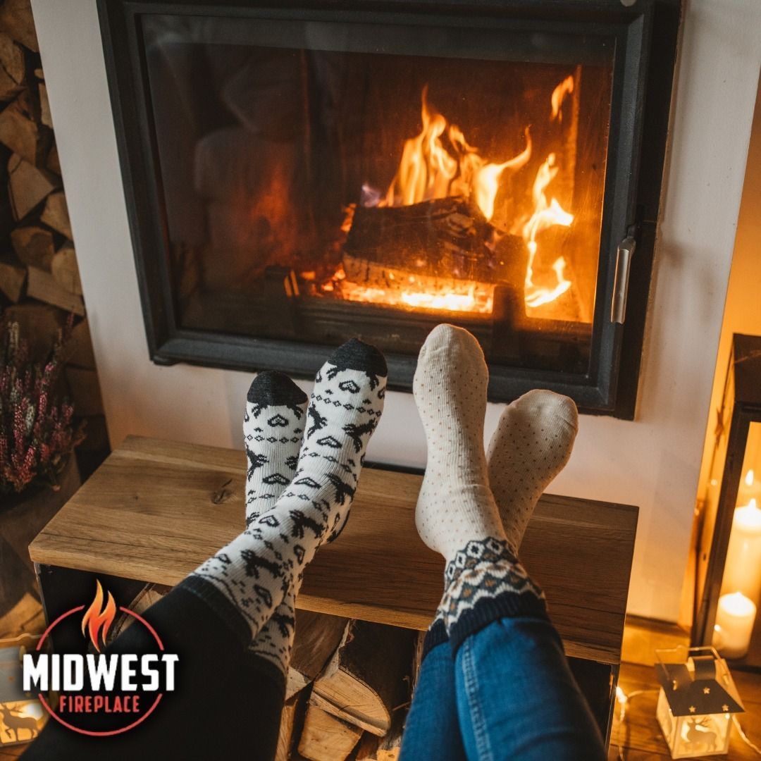 Feet in patterned socks near a burning fireplace.