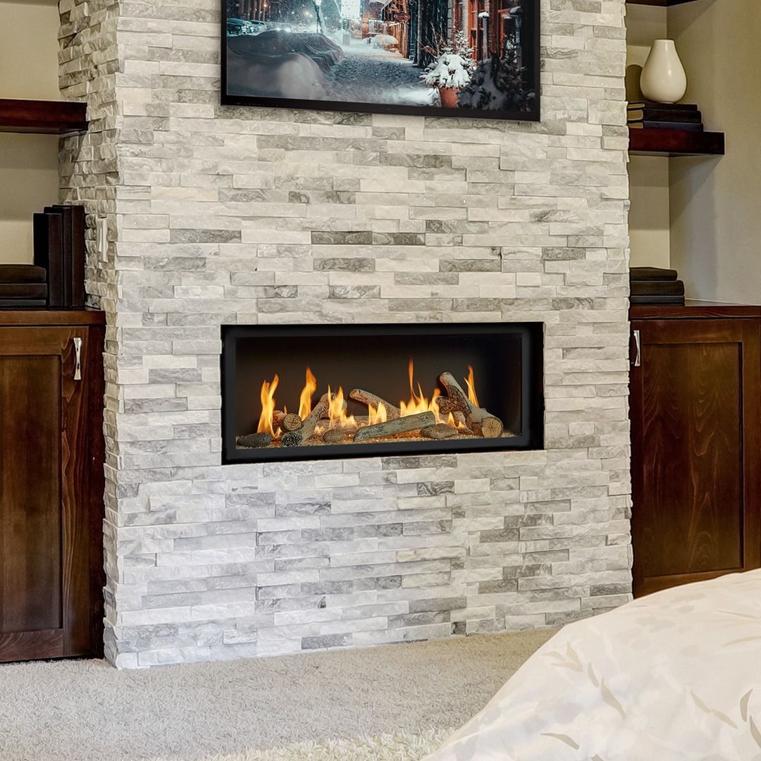 Fireplace with lit logs, in a gray stone wall, with a mounted TV above.