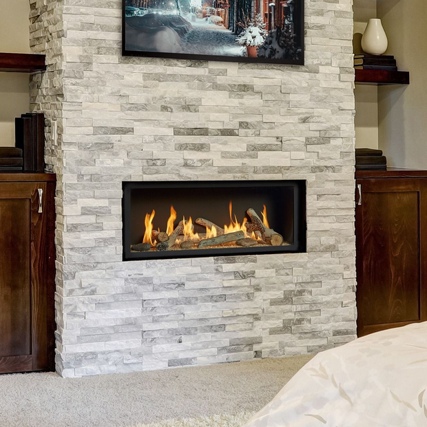 Fireplace with lit logs, in a gray stone wall, with a mounted TV above.