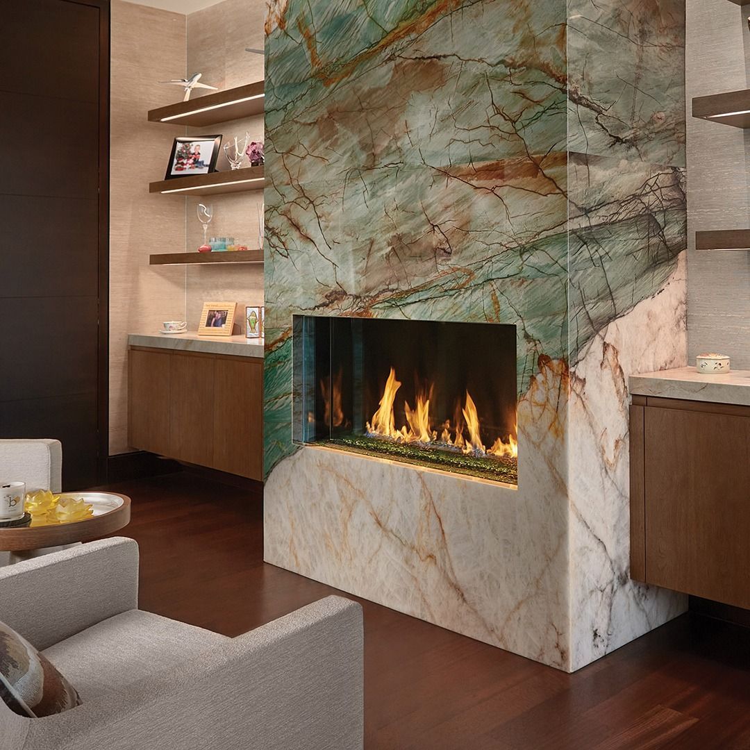 Fireplace with green and gold marble surround. Flames in the hearth, with wooden shelves and cabinetry.