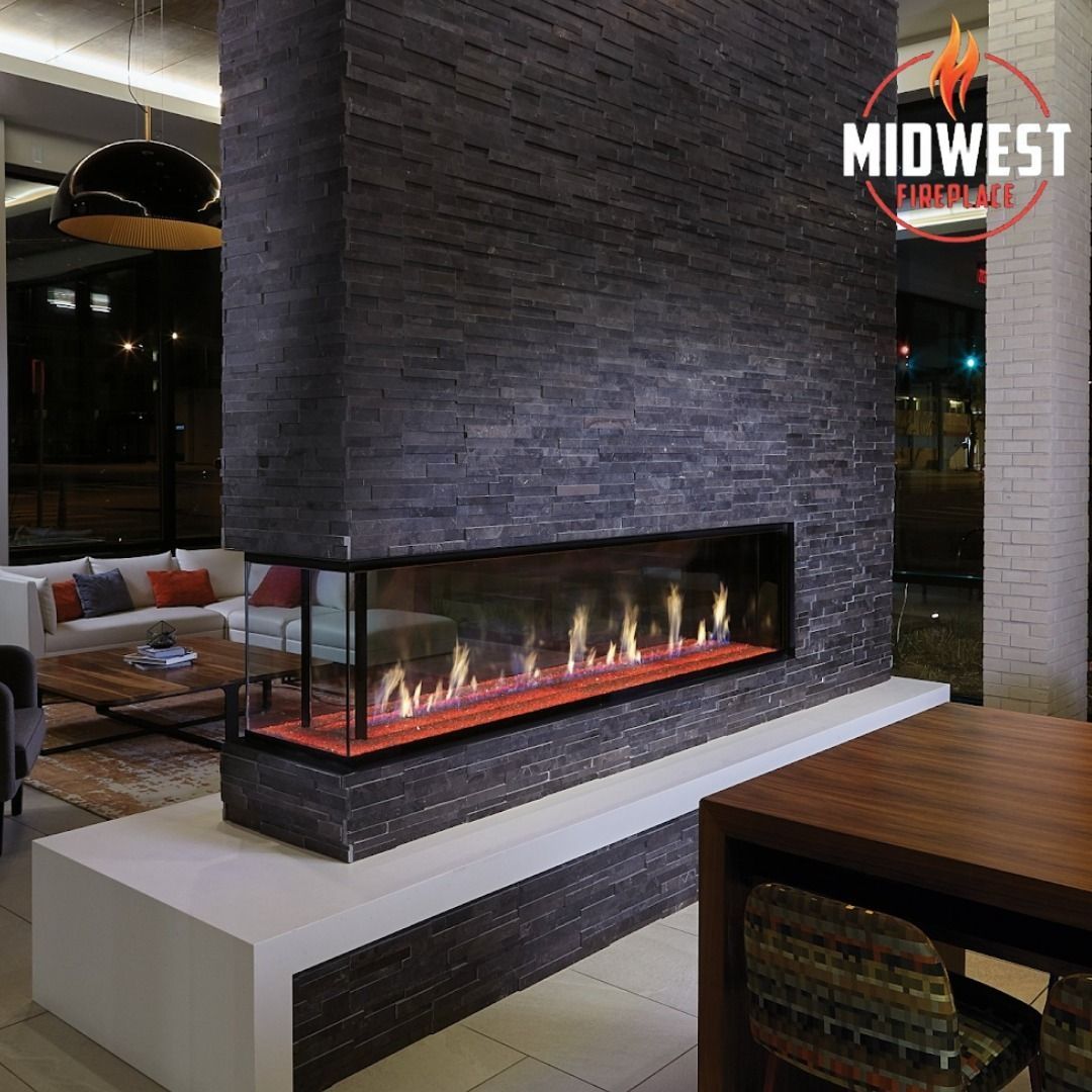 Modern fireplace with flames, built into a dark gray stone wall in a building's interior.
