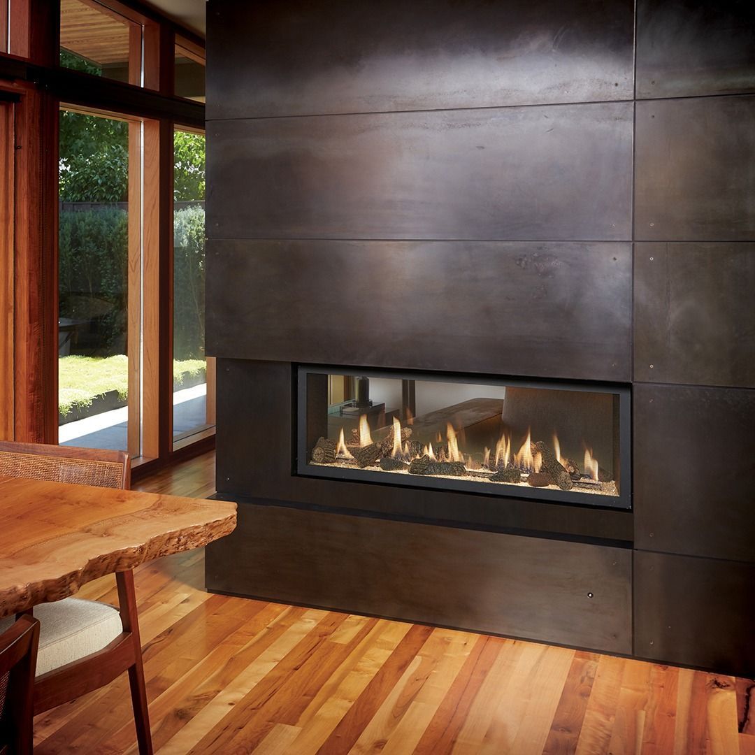 Modern fireplace with flame against a dark wall, hardwood floor, and window view.