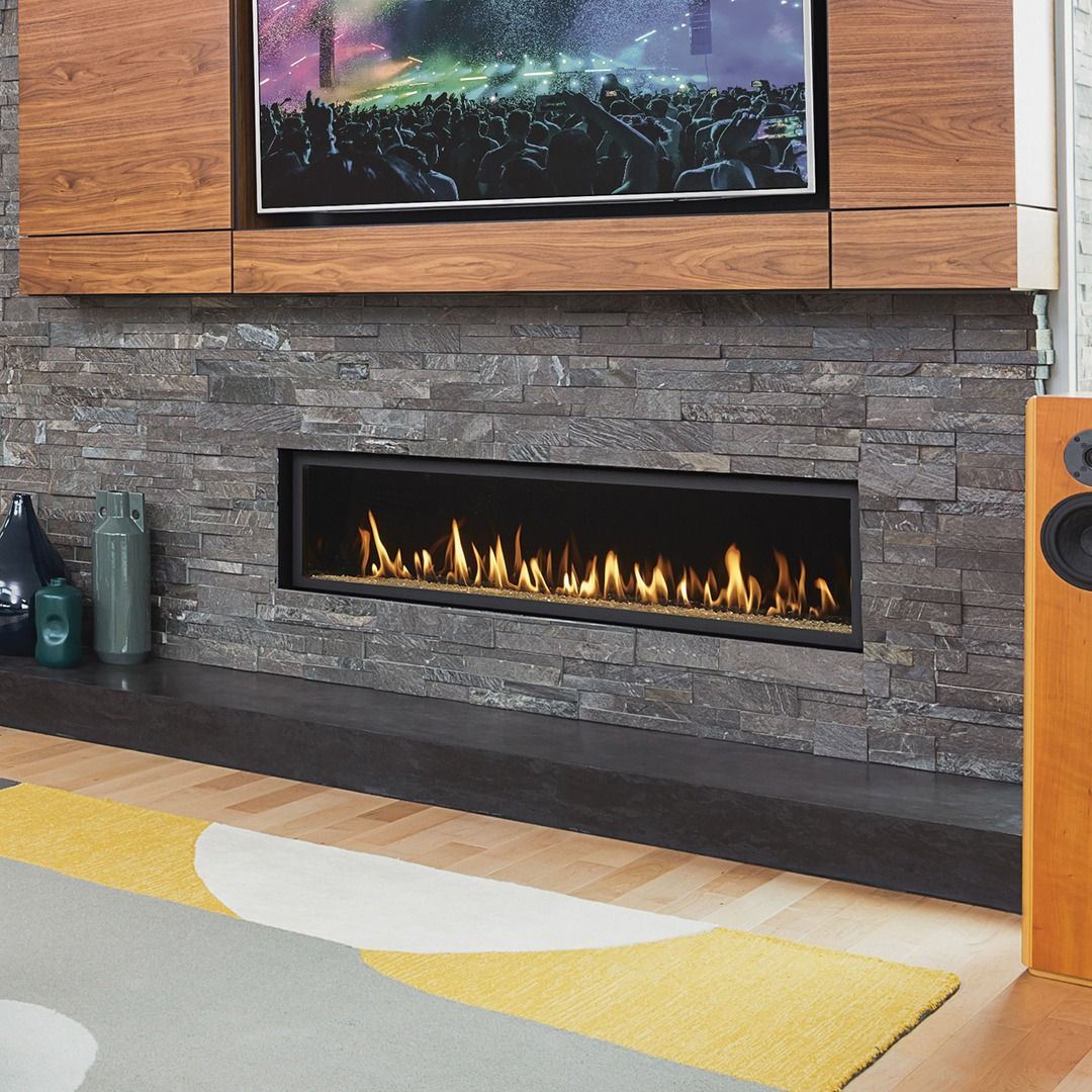 Fireplace with flames below a TV set in a stone wall.