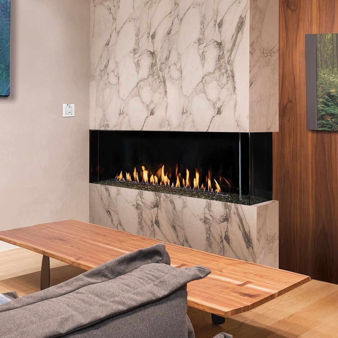 Fireplace with marble surround, flames, wood bench with blanket.