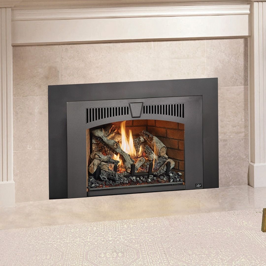 Gas fireplace with burning flames, in a brick-lined opening with dark metal frame, against tiled wall.