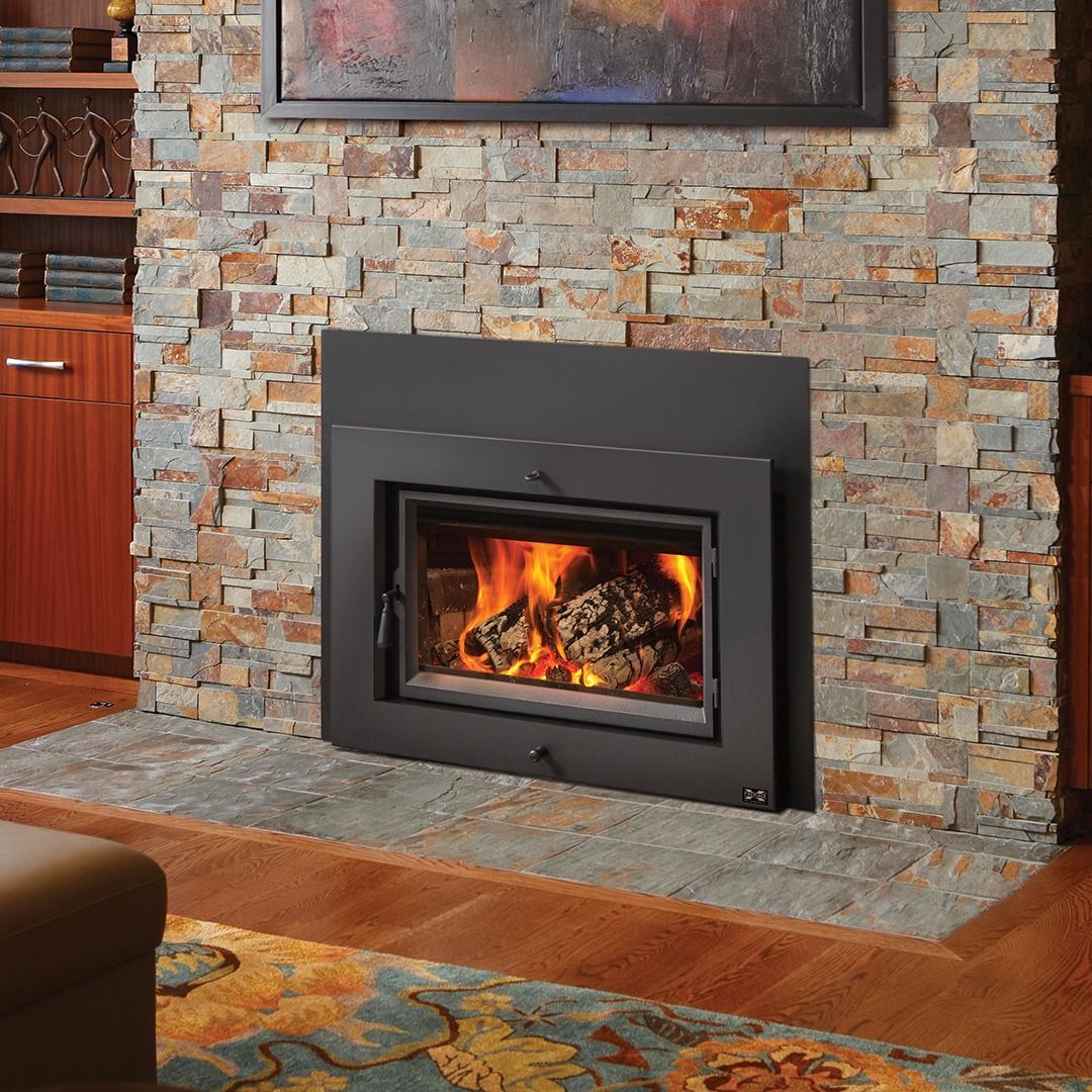 Fireplace with burning logs, set in a stone wall, framed by a black metal border.
