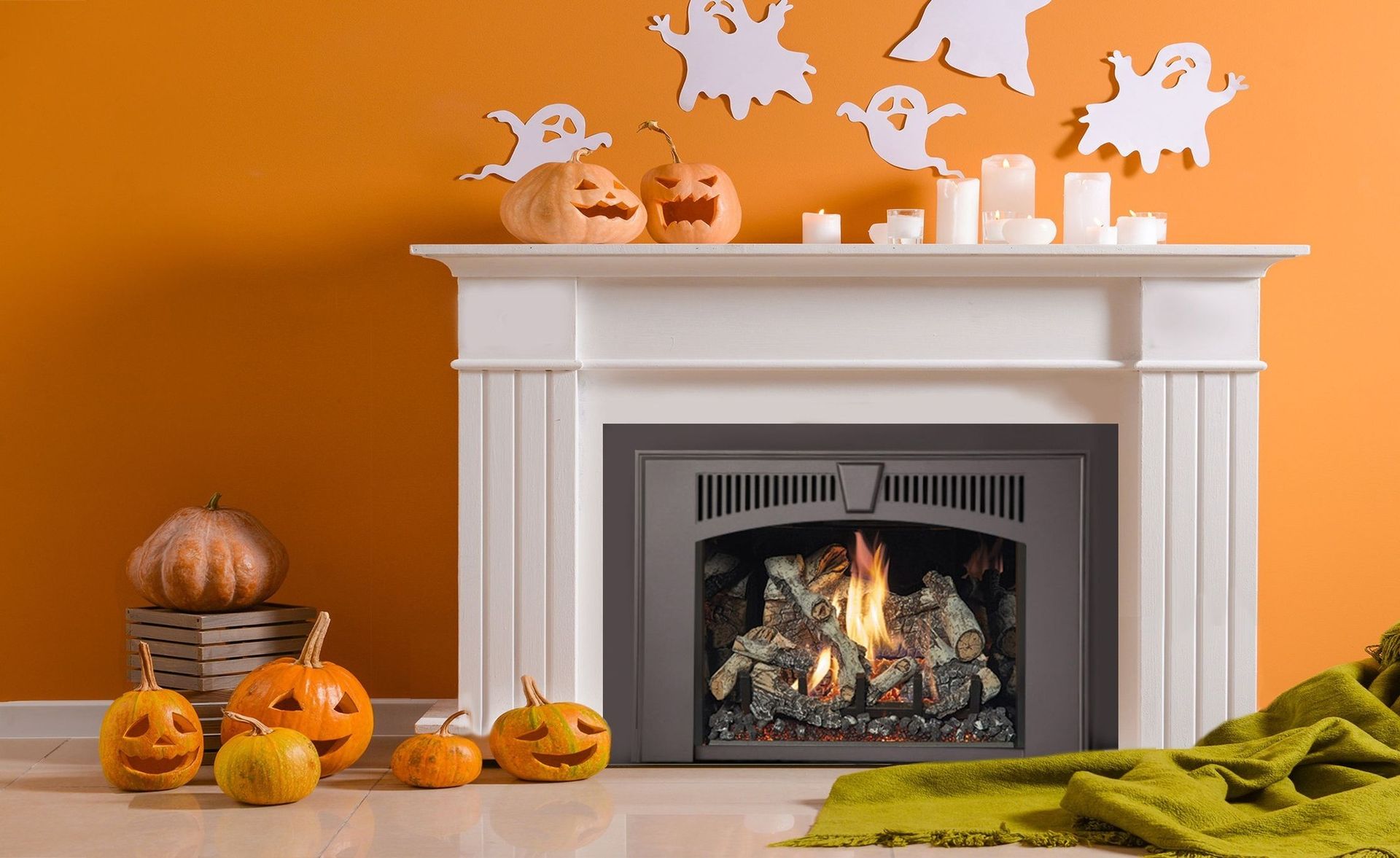 Fireplace decorated for Halloween with pumpkins, candles, and paper ghosts on an orange wall.