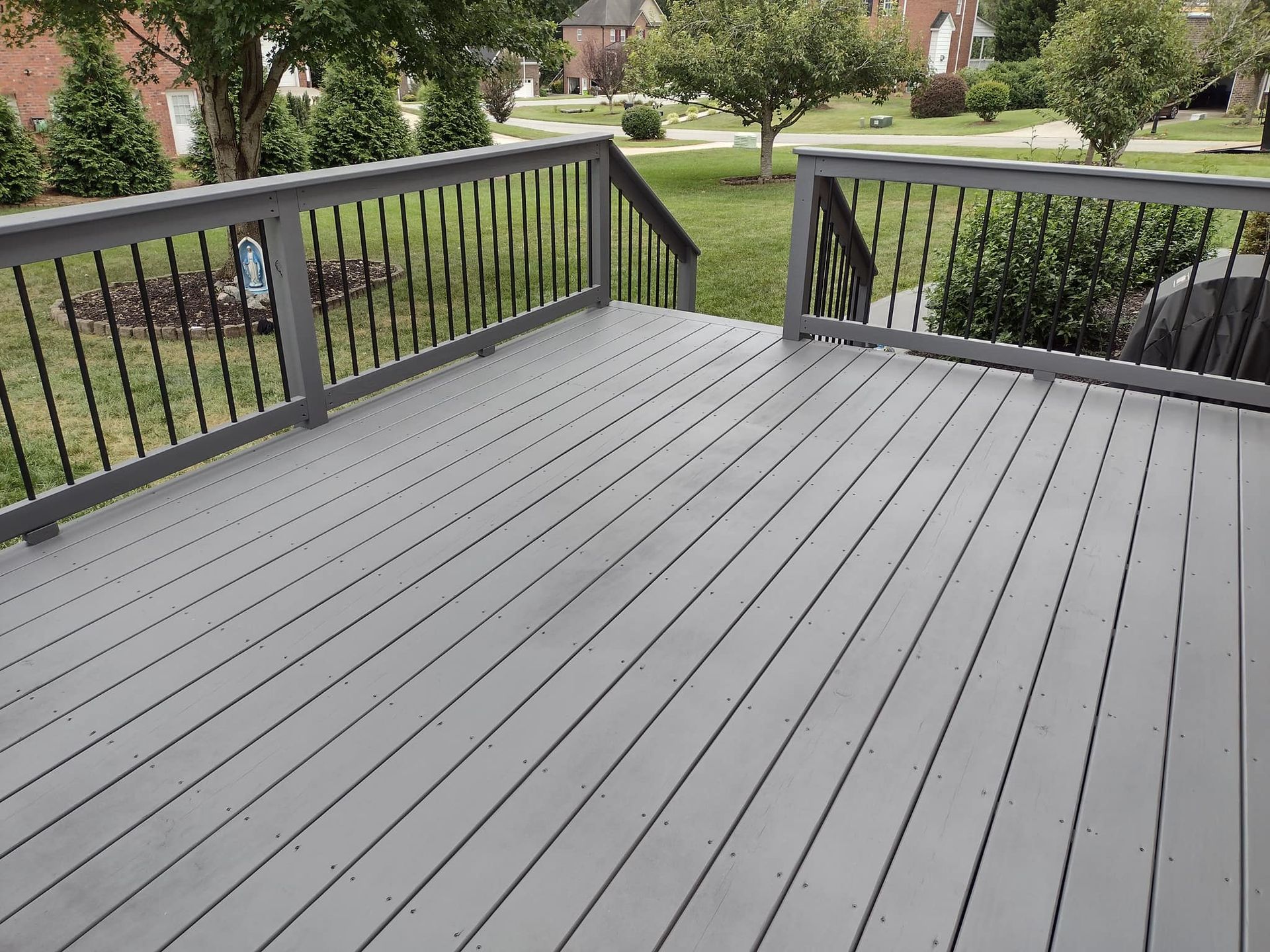 A gray deck with a black railing and stairs leading up to it.