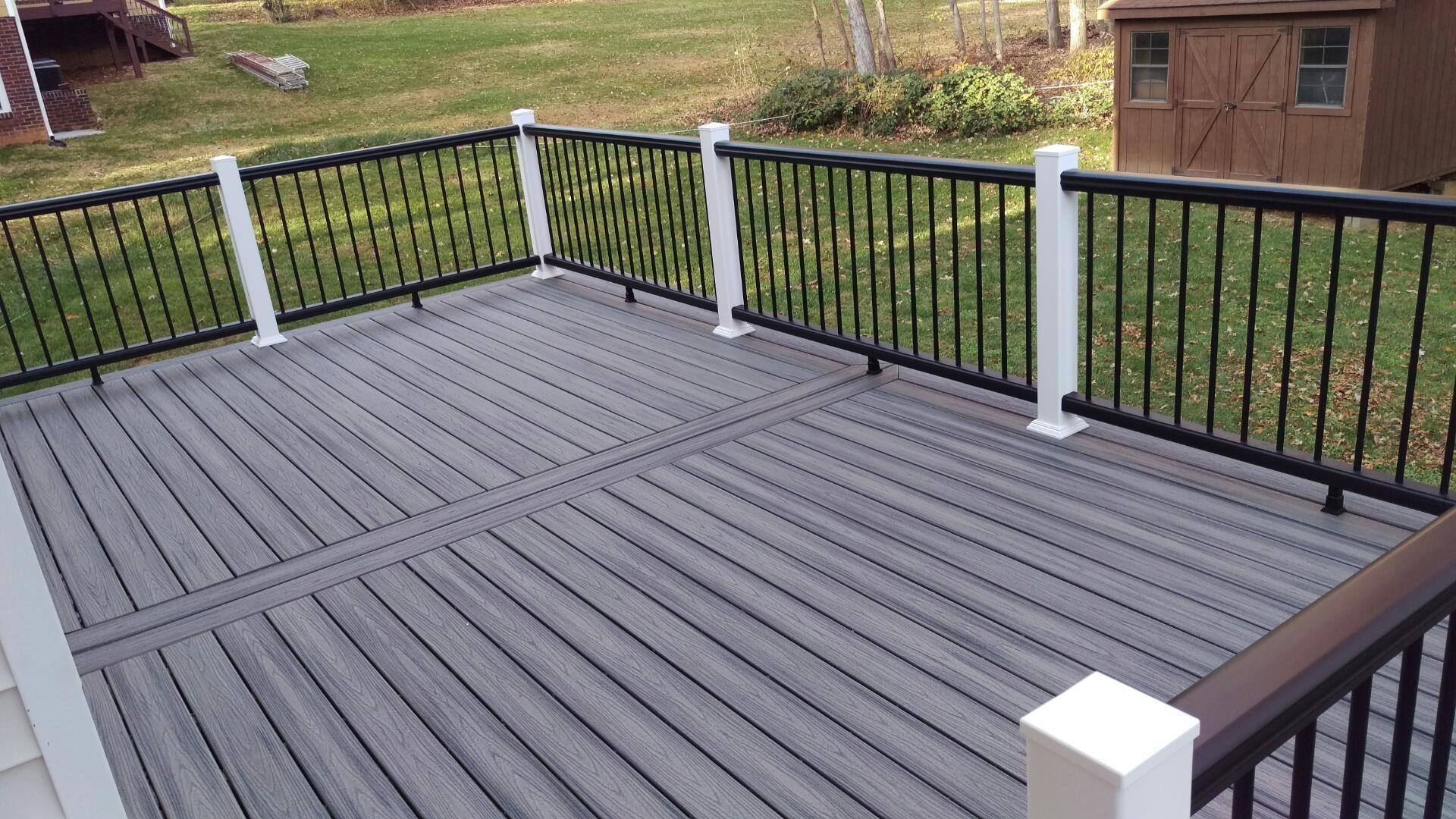 A deck with a black railing and a shed in the background.