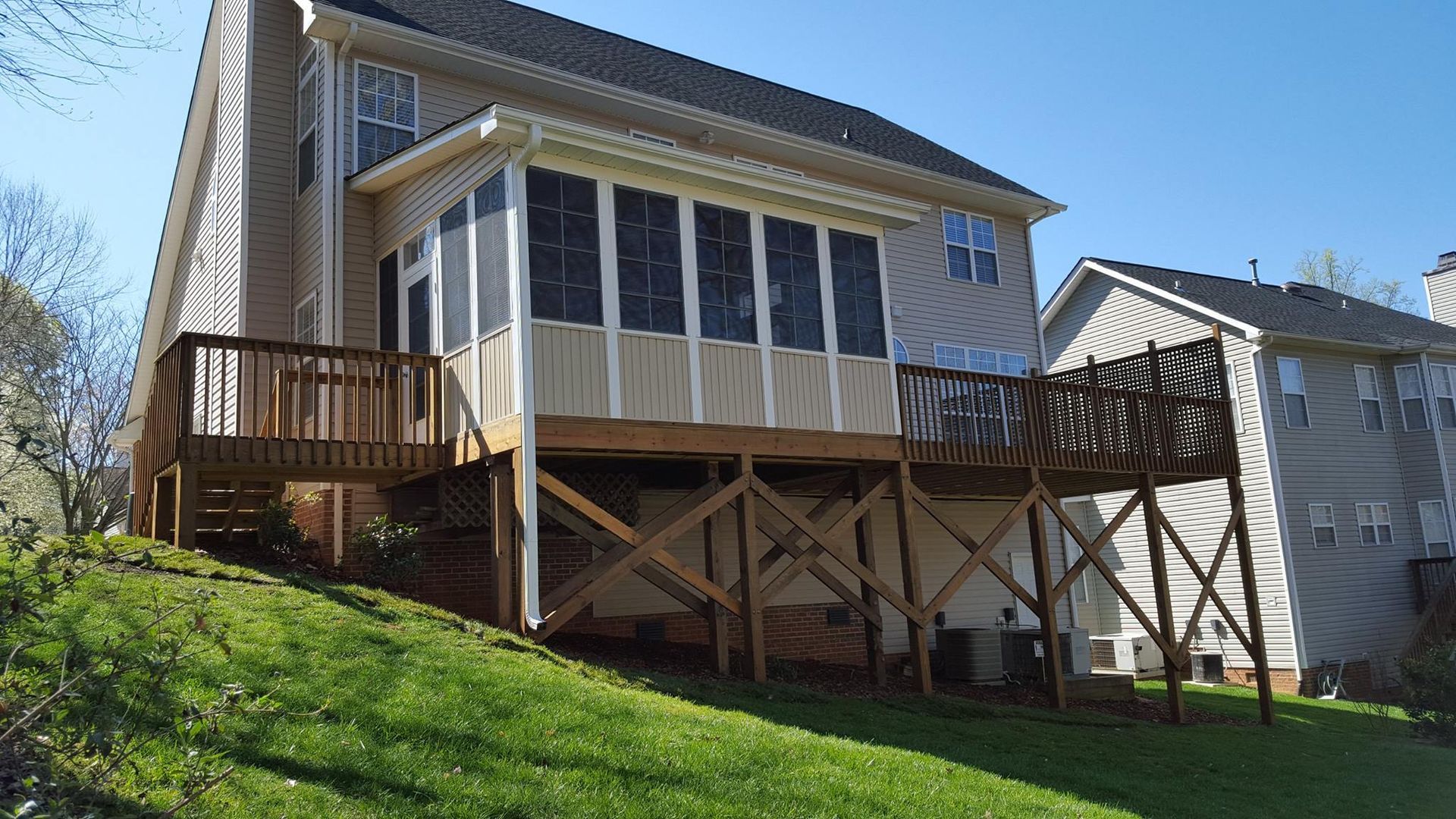A house with a screened in porch and a wooden deck.