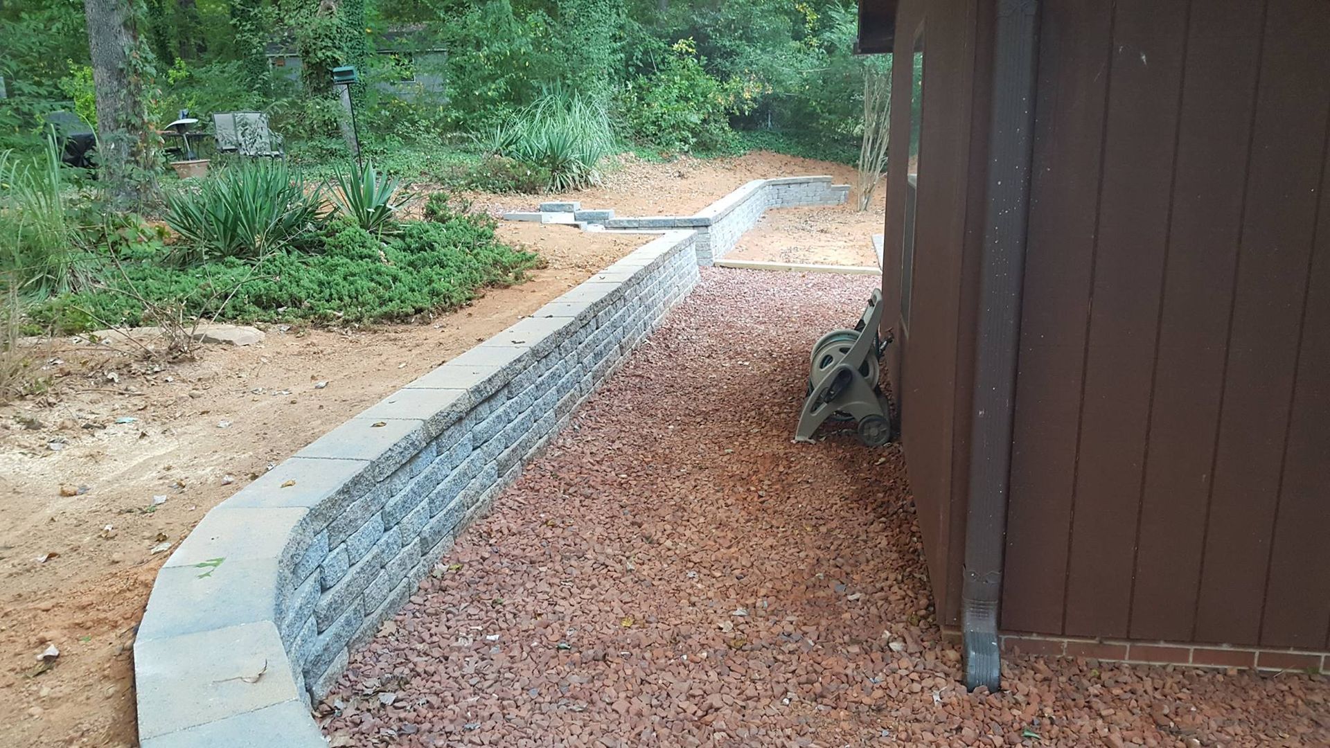 A turtle is sitting on the side of a building next to a stone wall.