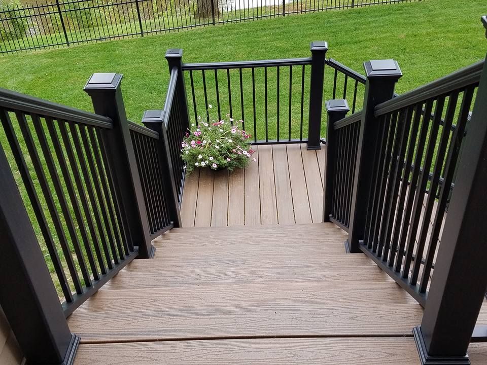 A set of stairs leading up to a deck with a black railing.