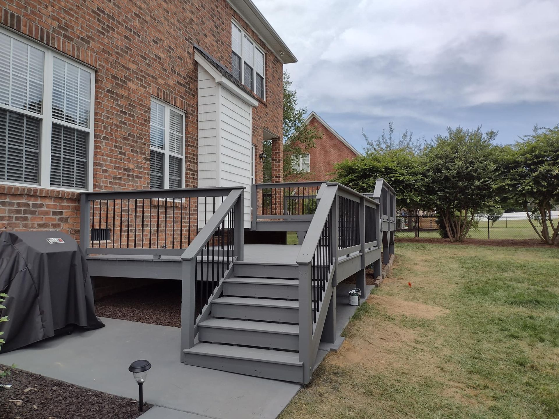 A brick house with a deck and stairs in front of it.